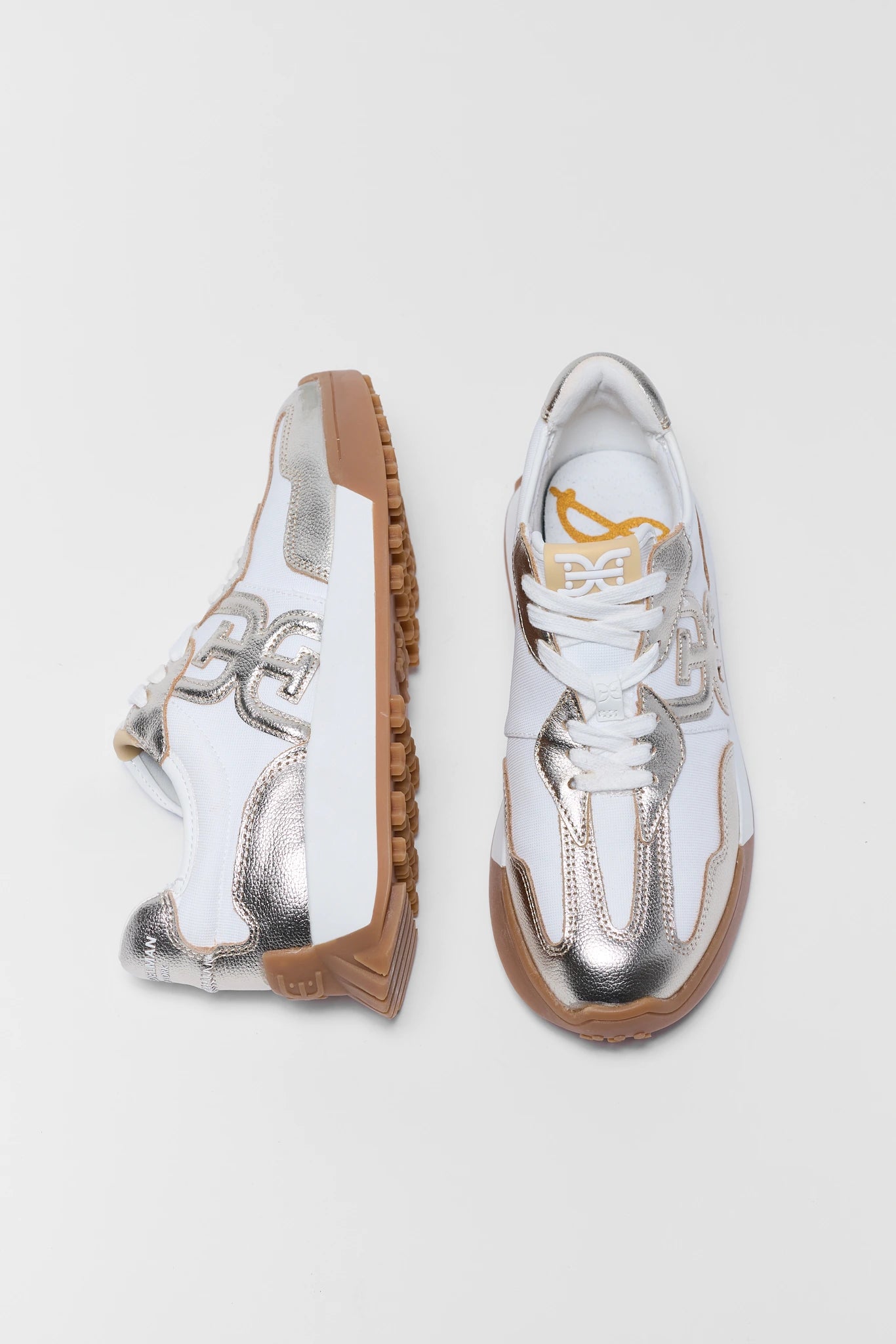 White sneakers with gold soles on a light gray background