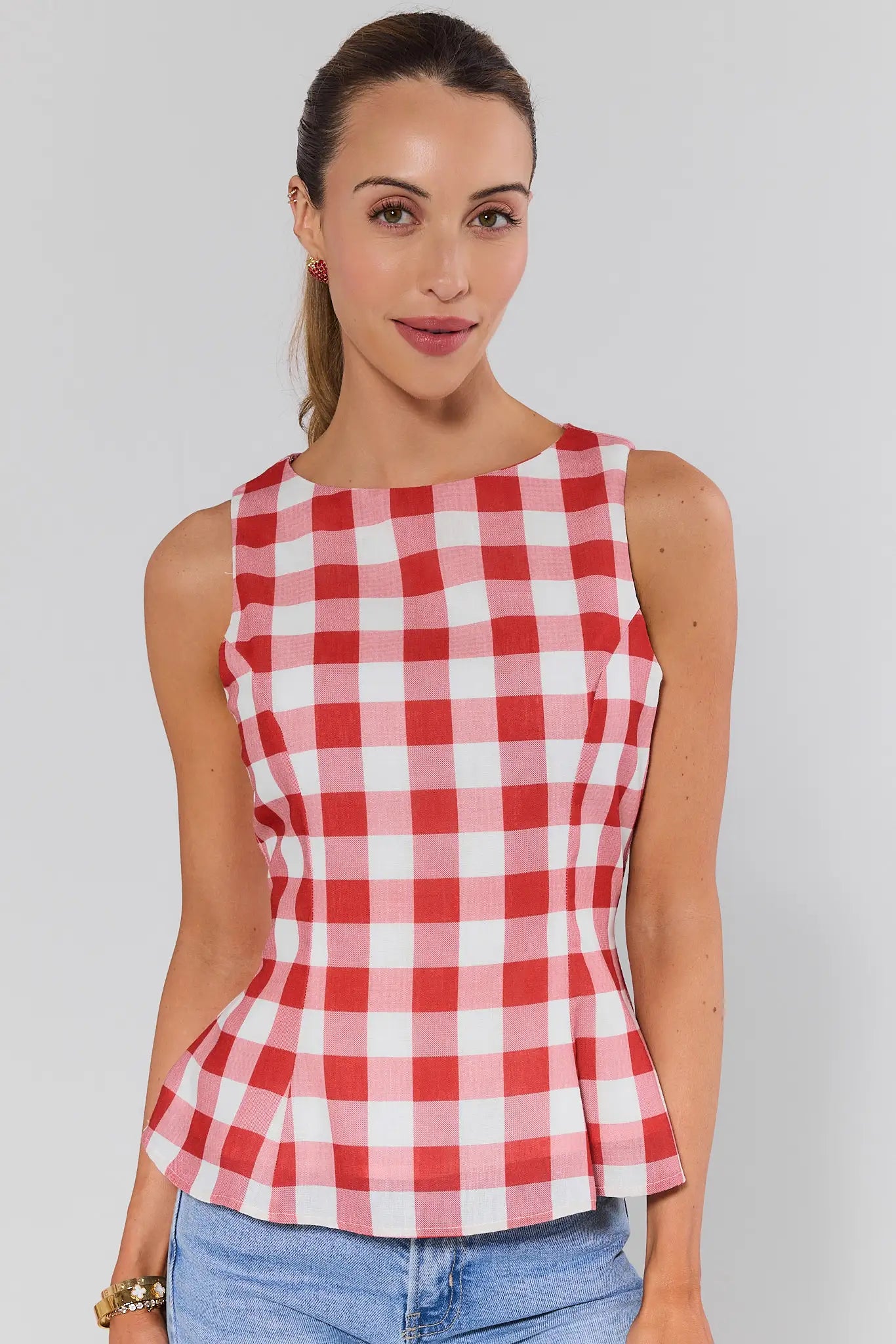 Woman wearing a red and white checkered sleeveless top against a plain background