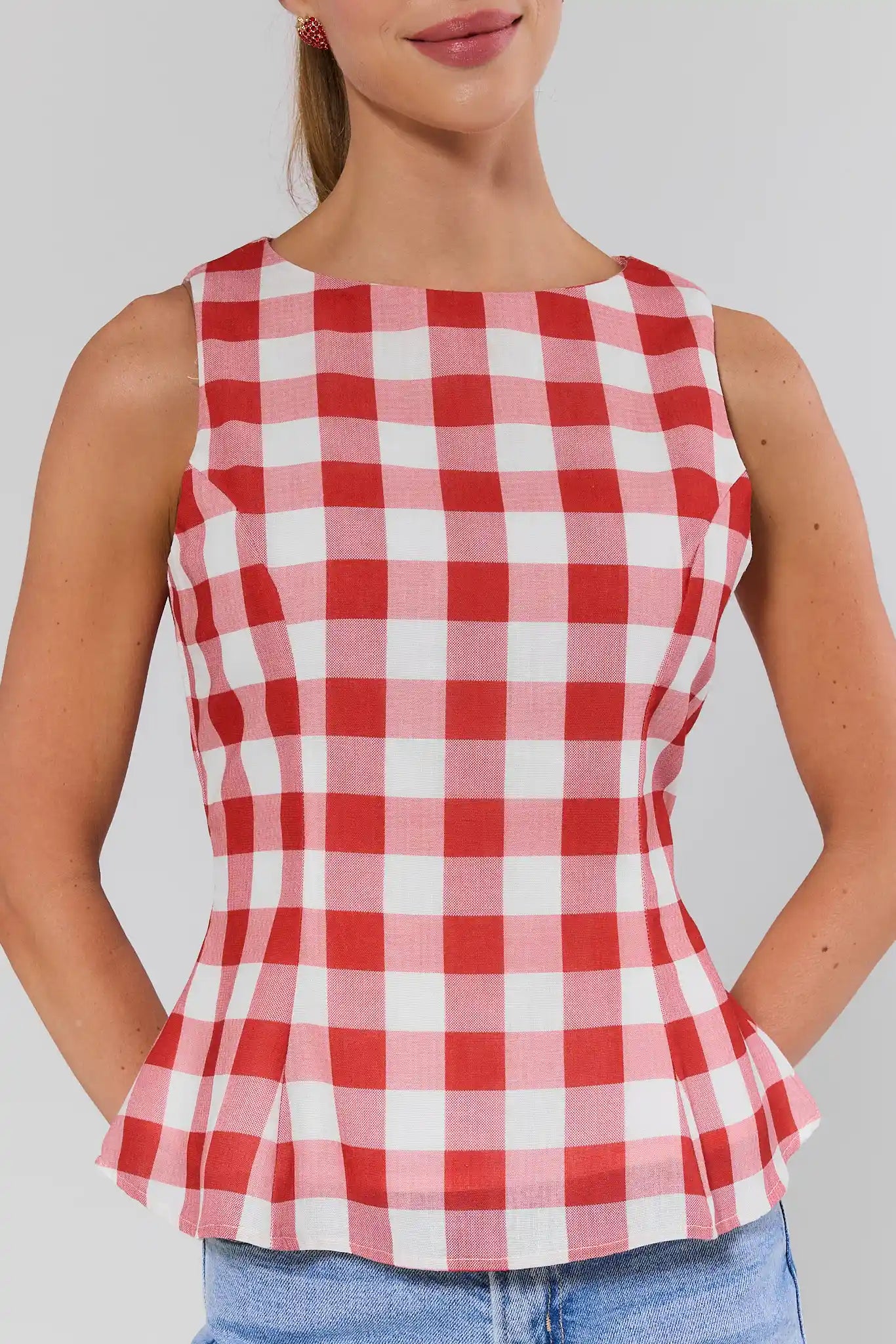 close up Red and white checkered sleeveless top worn by a person on a plain background