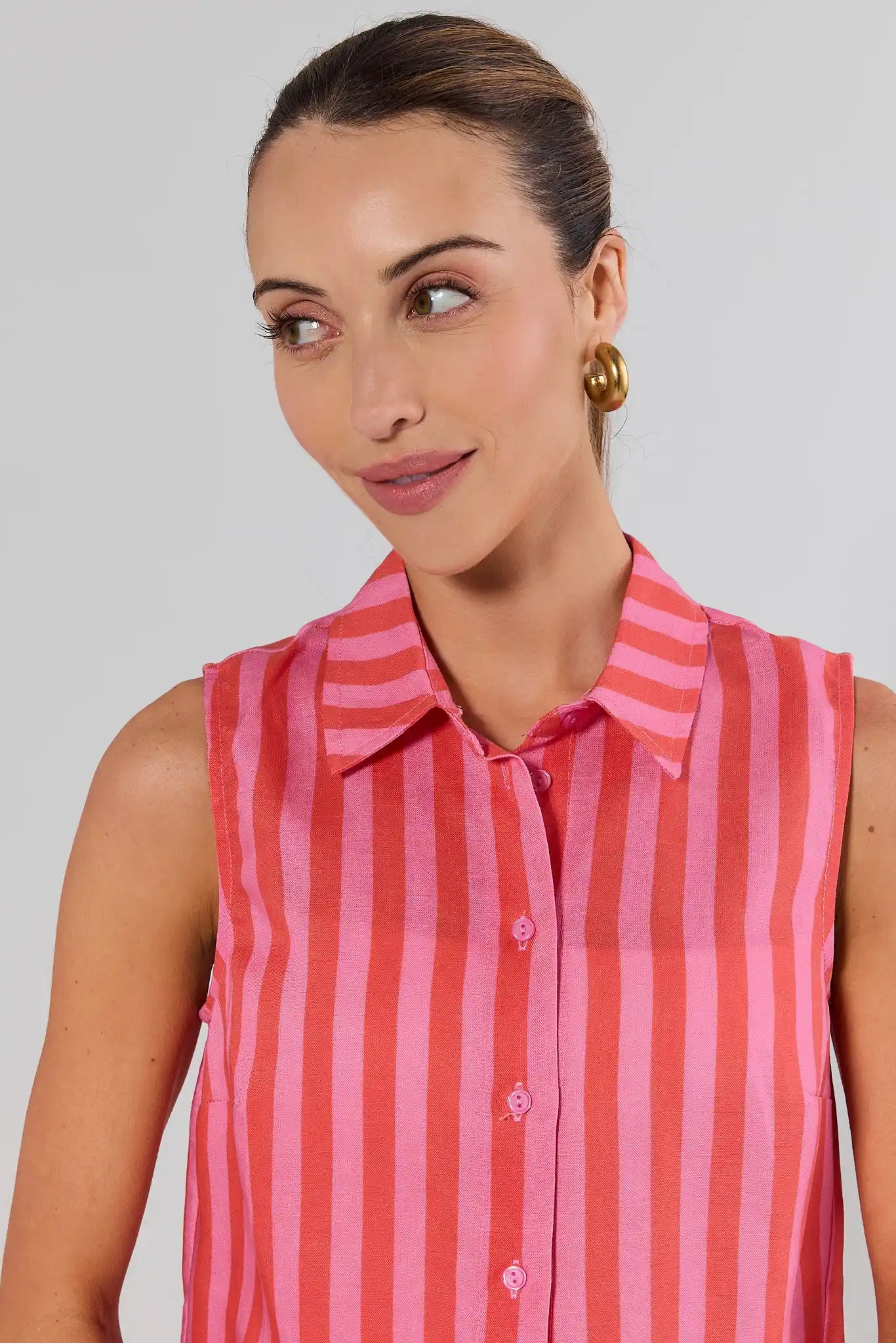 close up Woman wearing a pink and red striped sleeveless shirt against a plain background