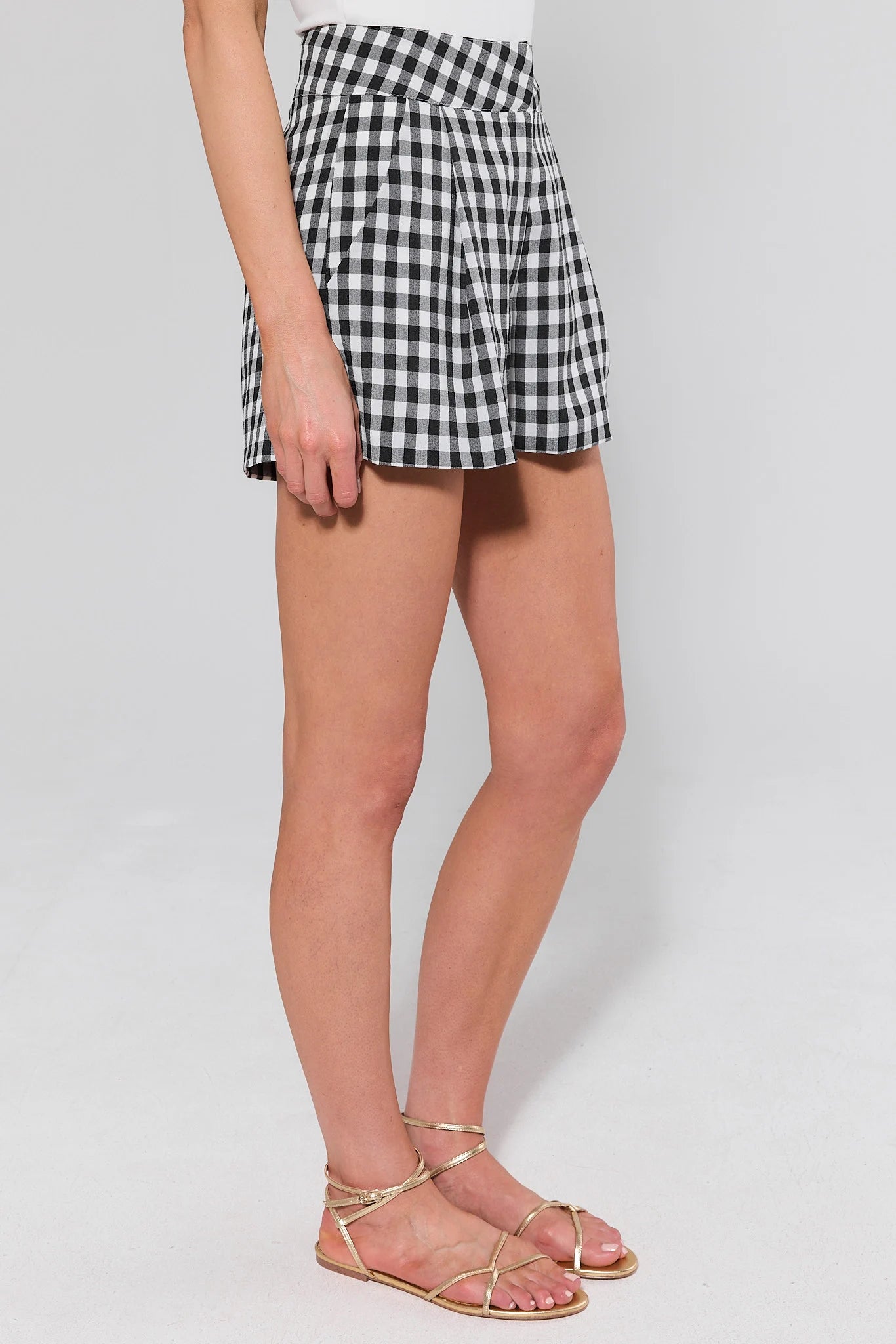 side shot Person wearing a black and white checkered skirt on a plain background