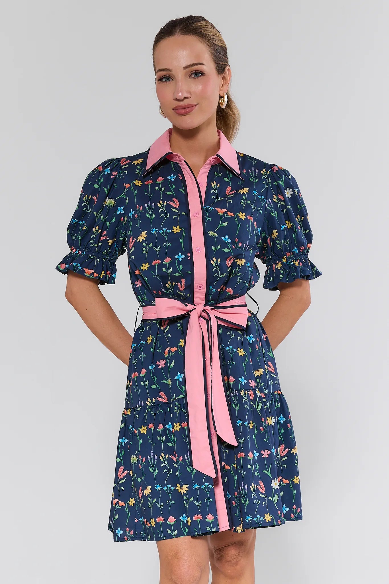 Woman wearing a navy floral dress with pink accents on a white background