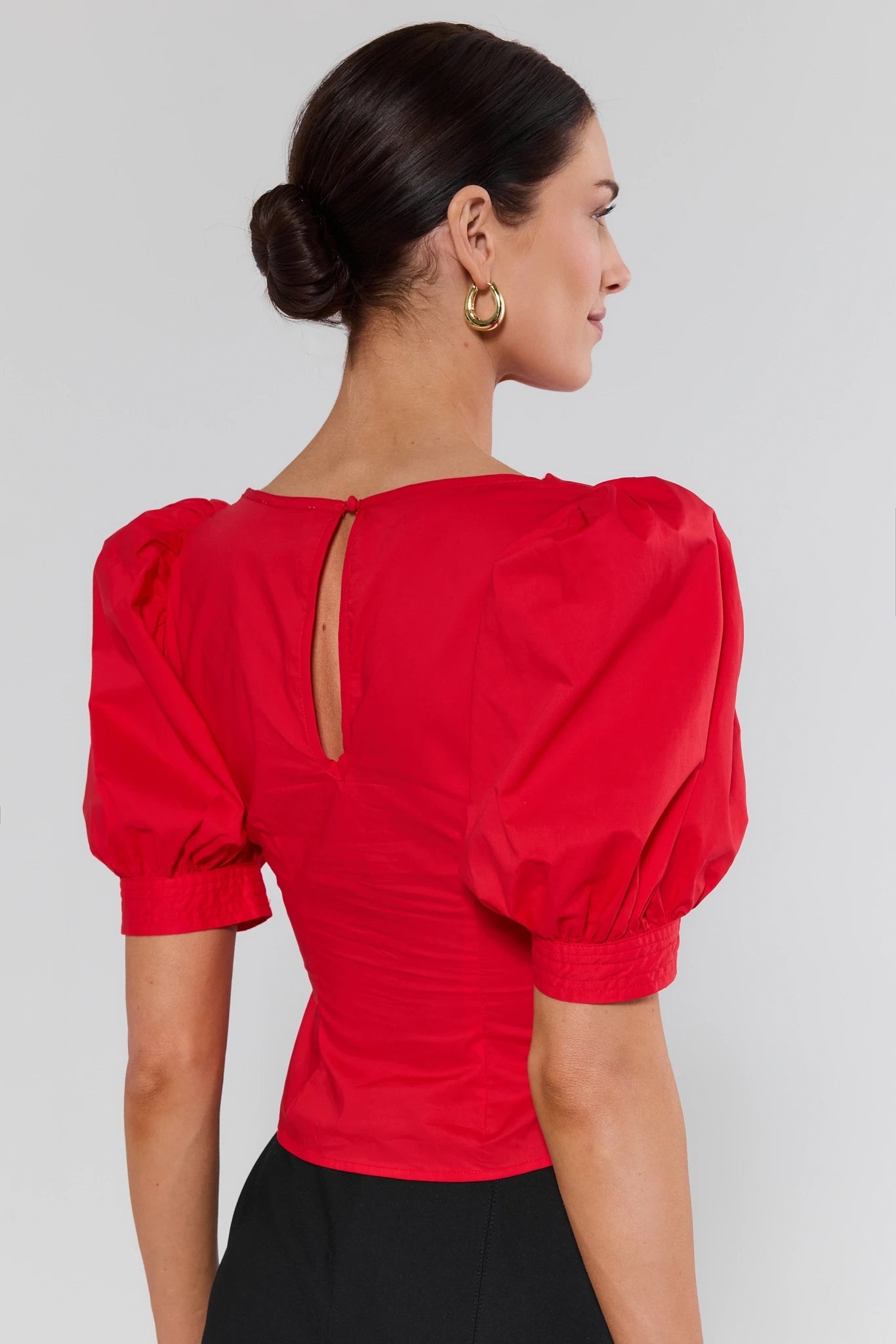 Woman wearing a red blouse with puff sleeves on background