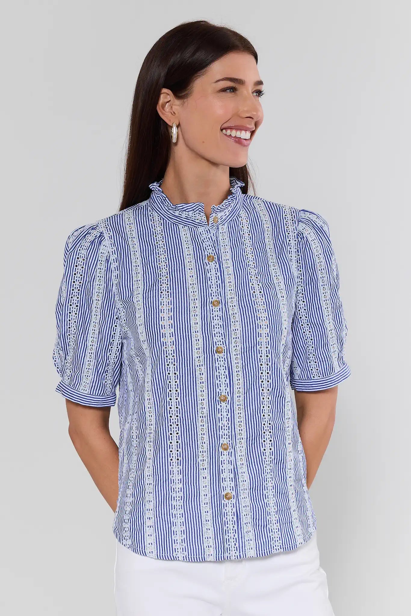 Woman wearing a blue and white patterned blouse against a plain background