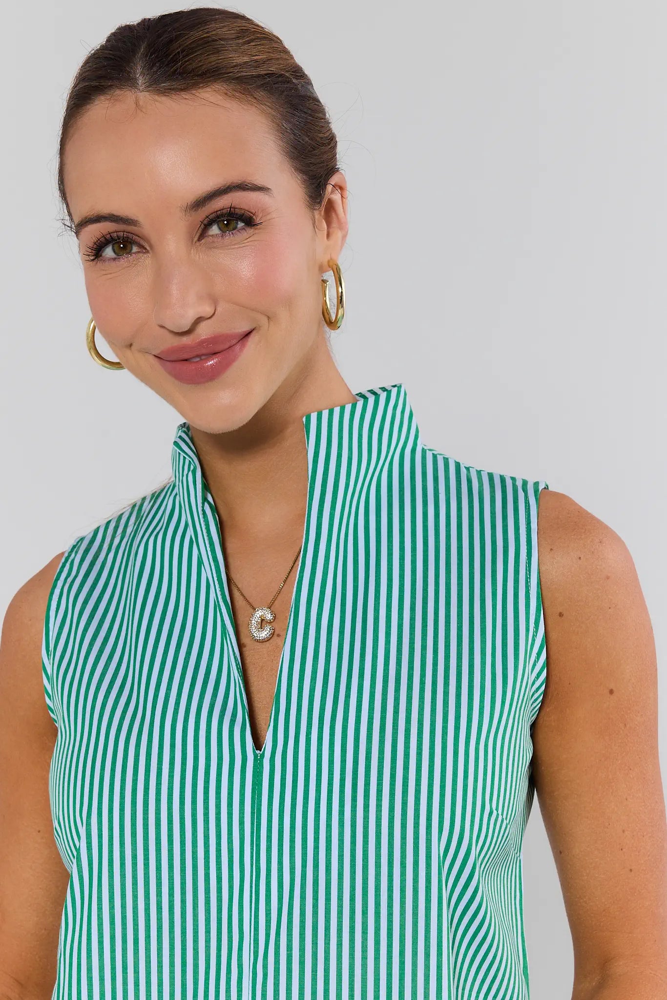 Woman wearing a green and white striped sleeveless top against a plain background