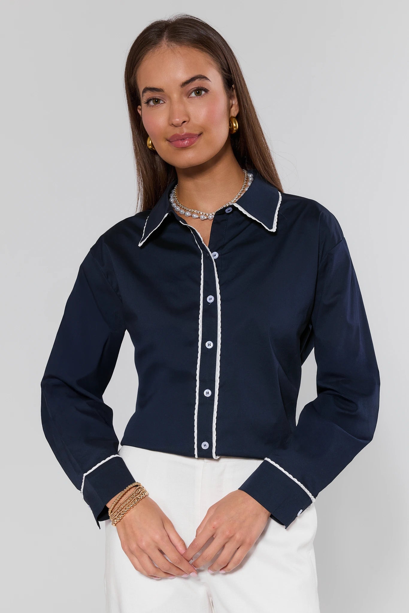 Woman wearing a navy blue shirt with white trim on a plain background