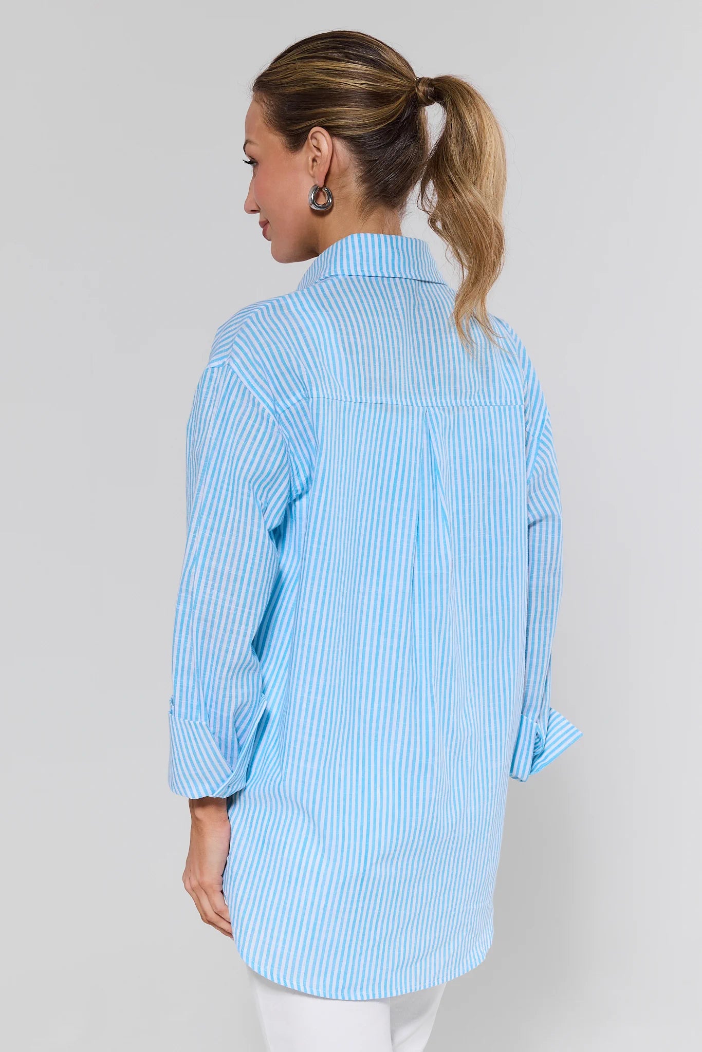 Woman wearing a light blue striped shirt against a plain background