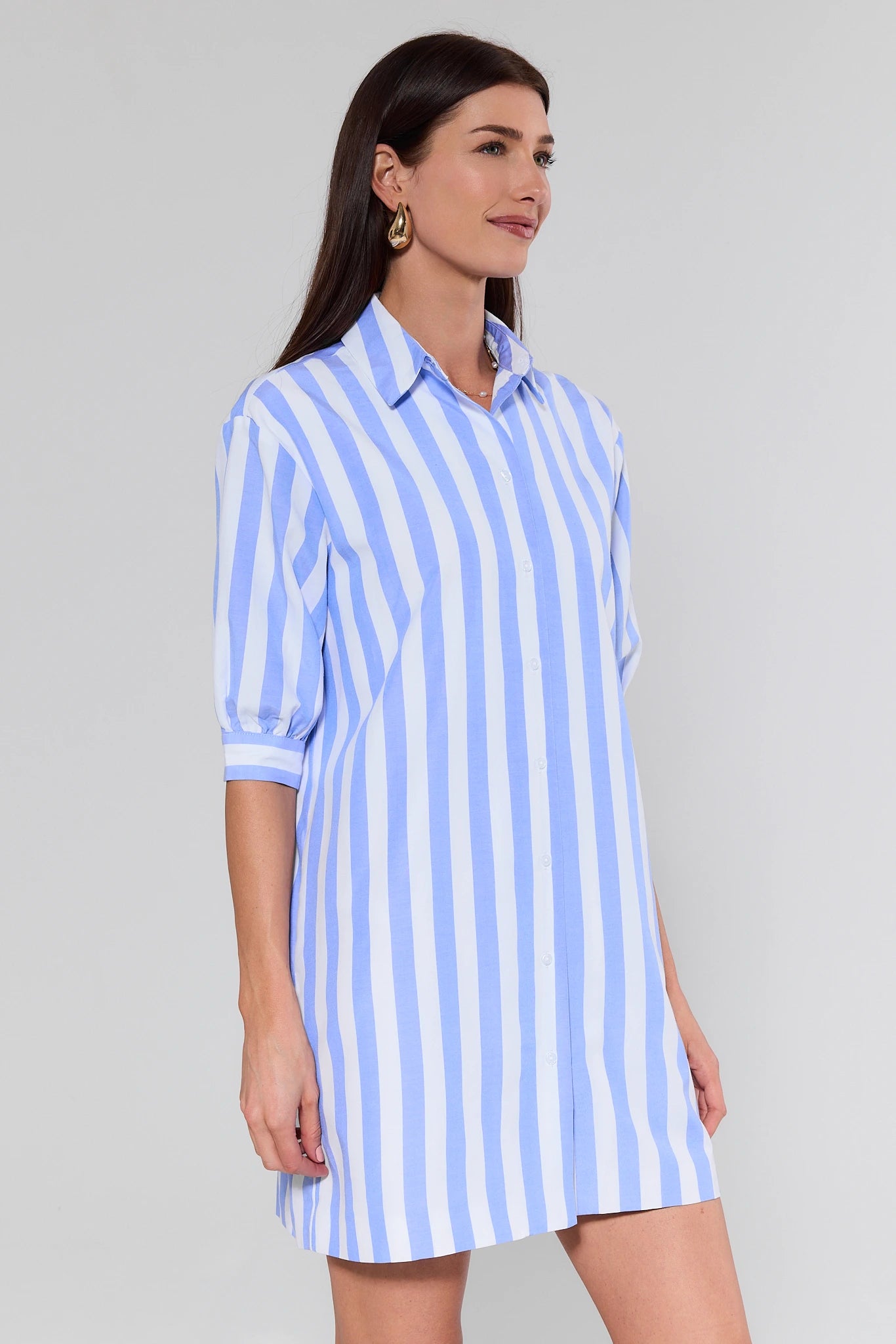Woman wearing a blue and white striped dress against a gray background
