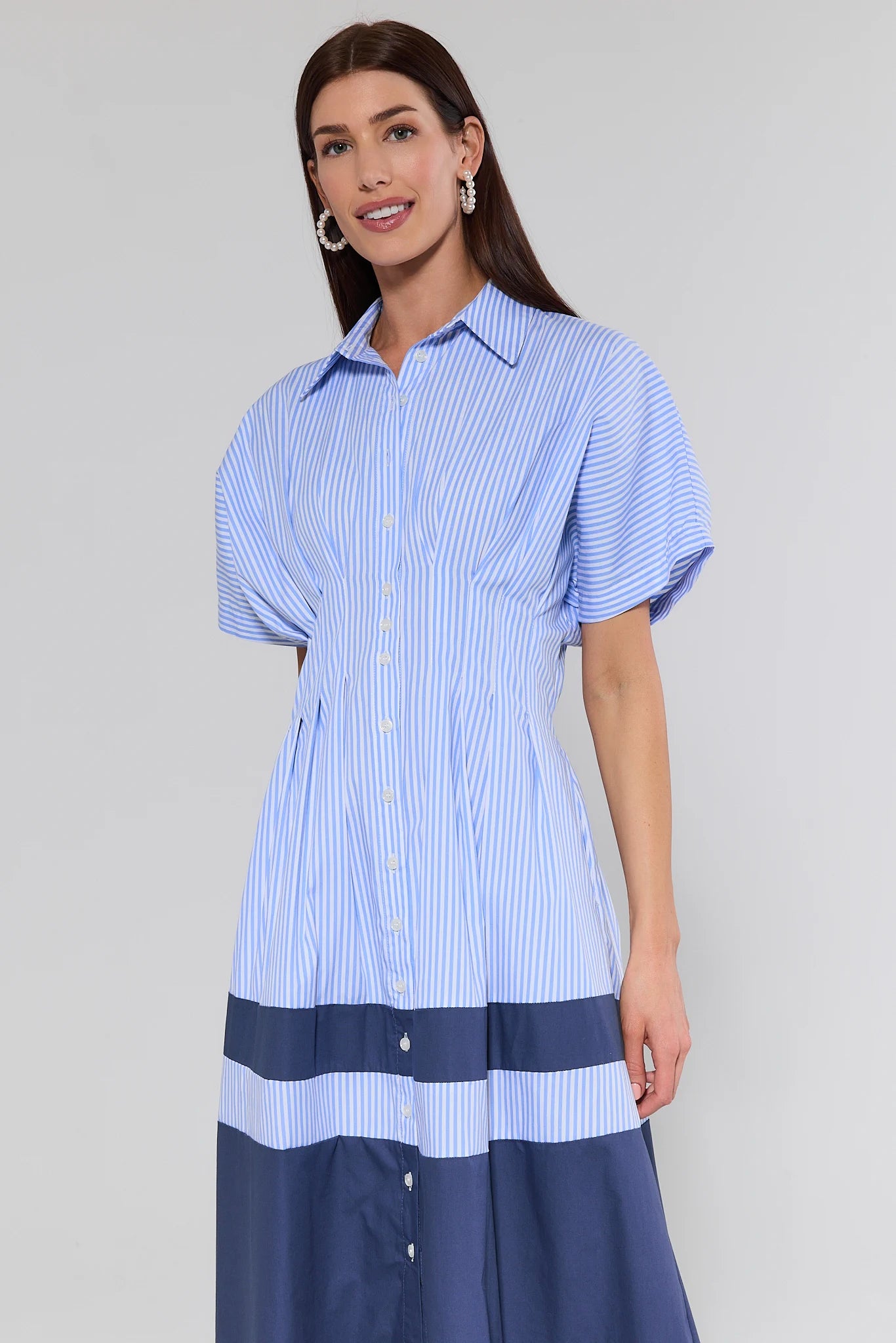 Woman wearing a blue and white striped dress against a plain background