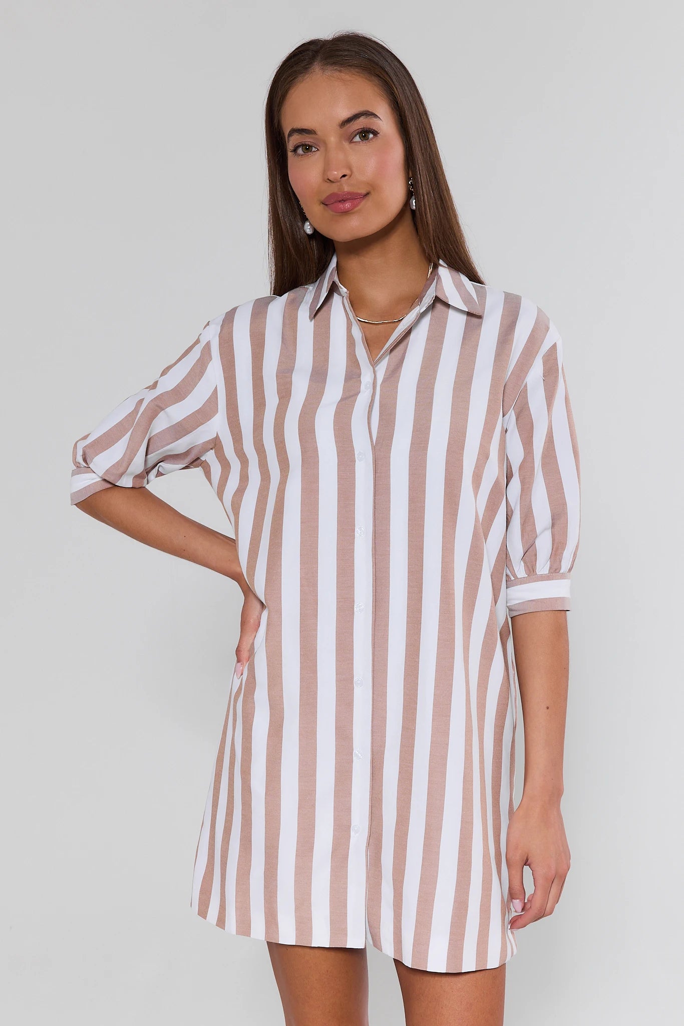 Woman wearing a striped shirt dress against a plain background