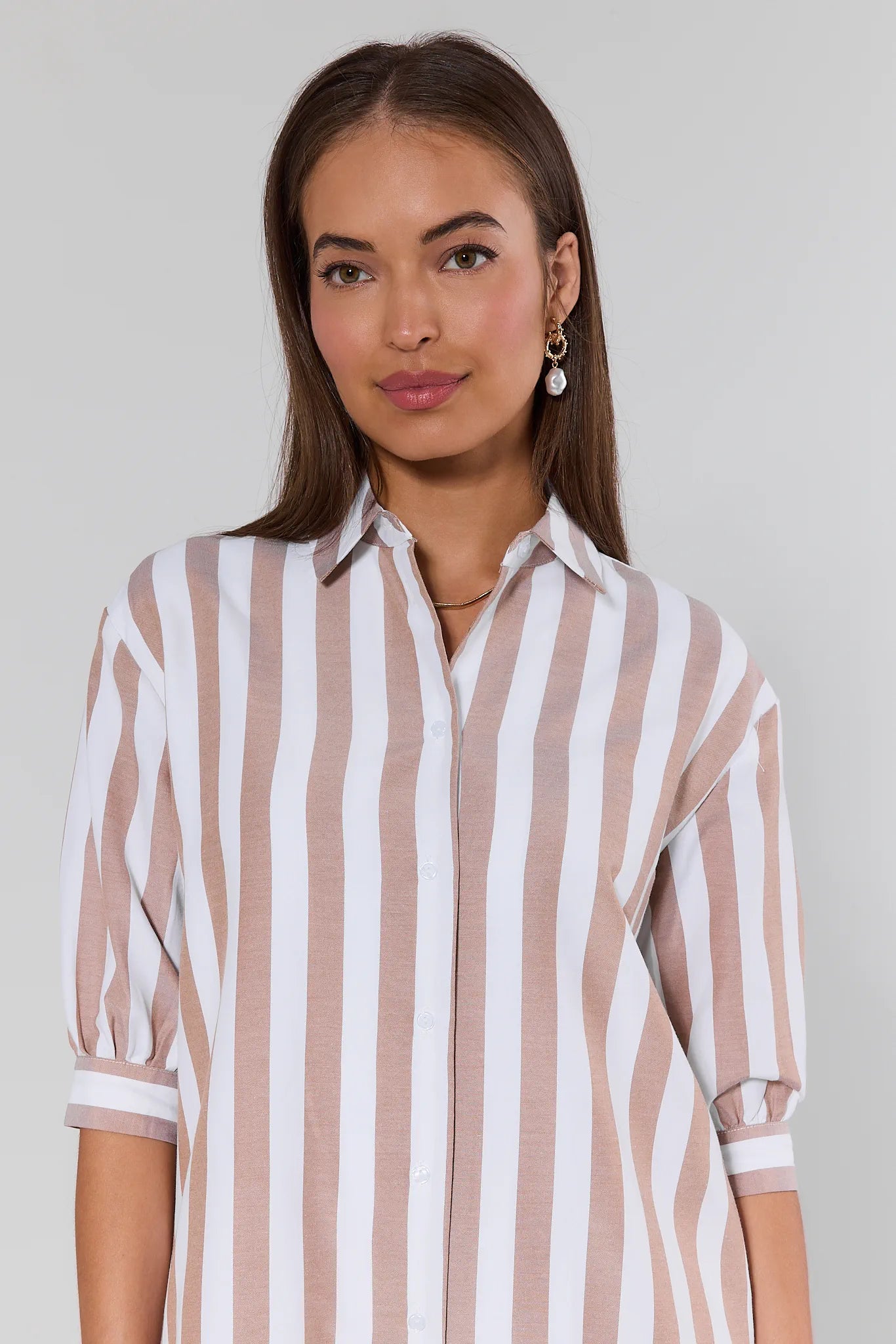 Woman wearing a striped shirt against a plain background