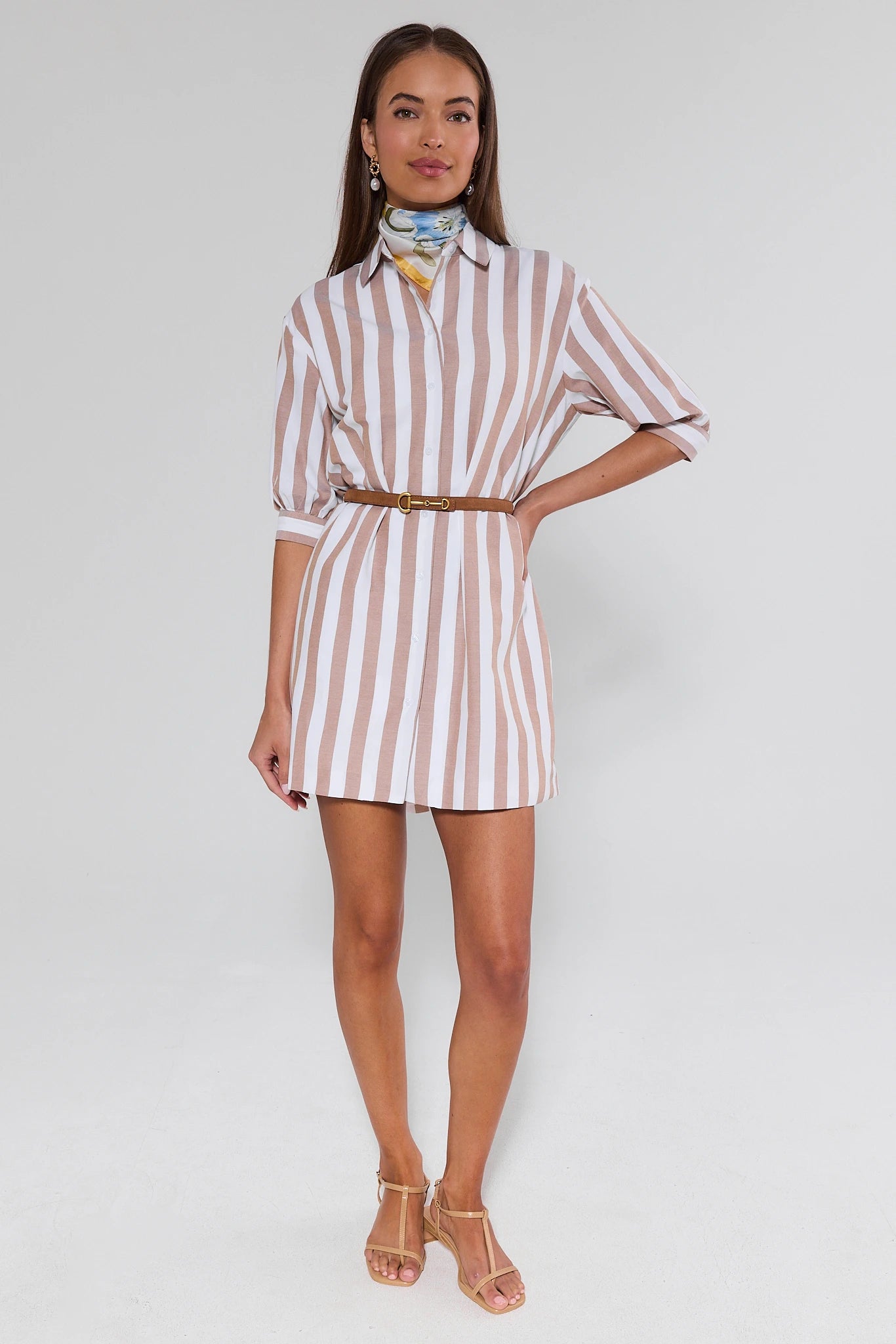 Woman wearing a striped dress with a belt on a white background