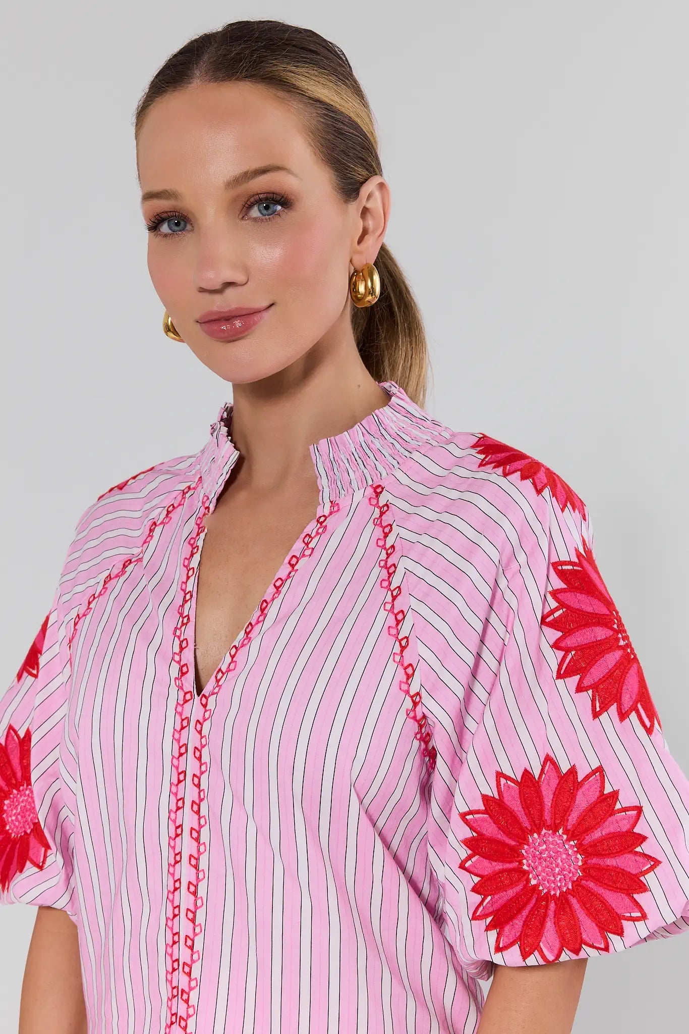 Woman wearing a pink top with floral patterns on a plain background