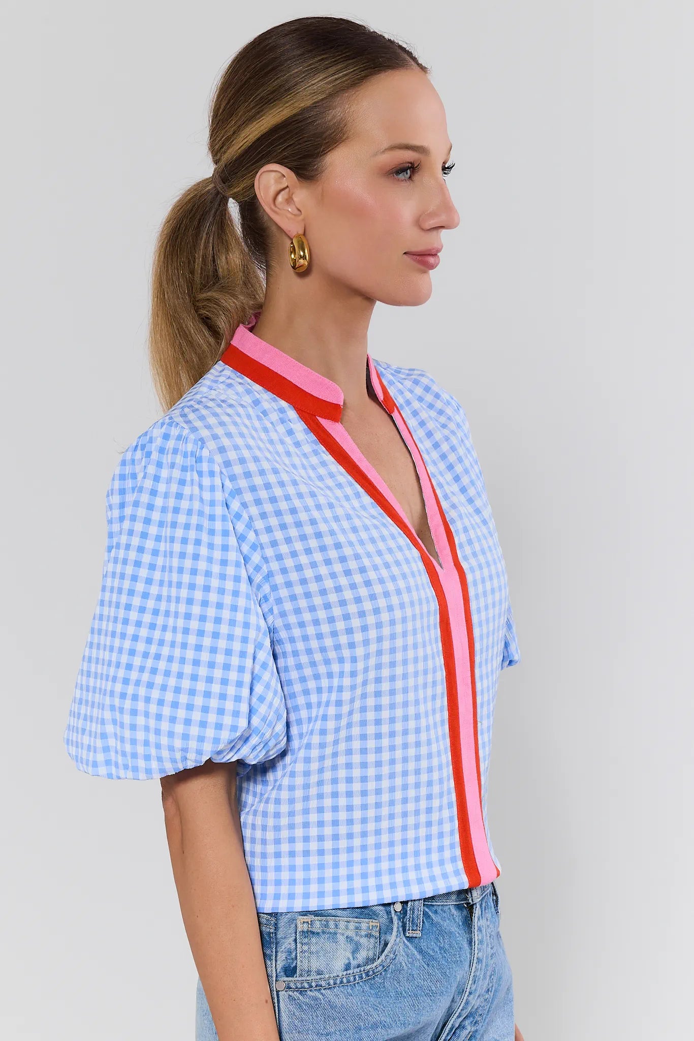 Woman wearing a blue checkered blouse with red trim on a background