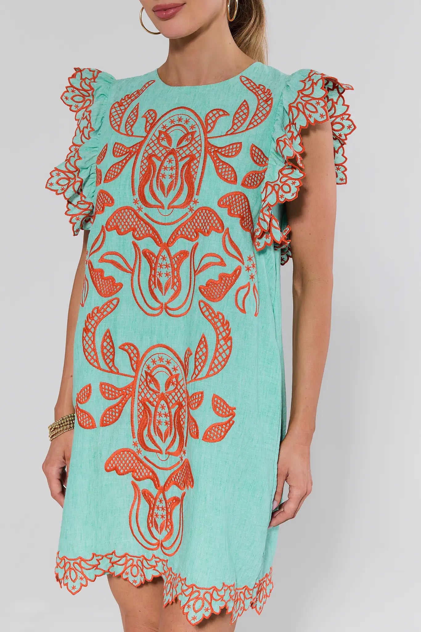 Woman wearing a turquoise dress with orange tribal patterns on a white background