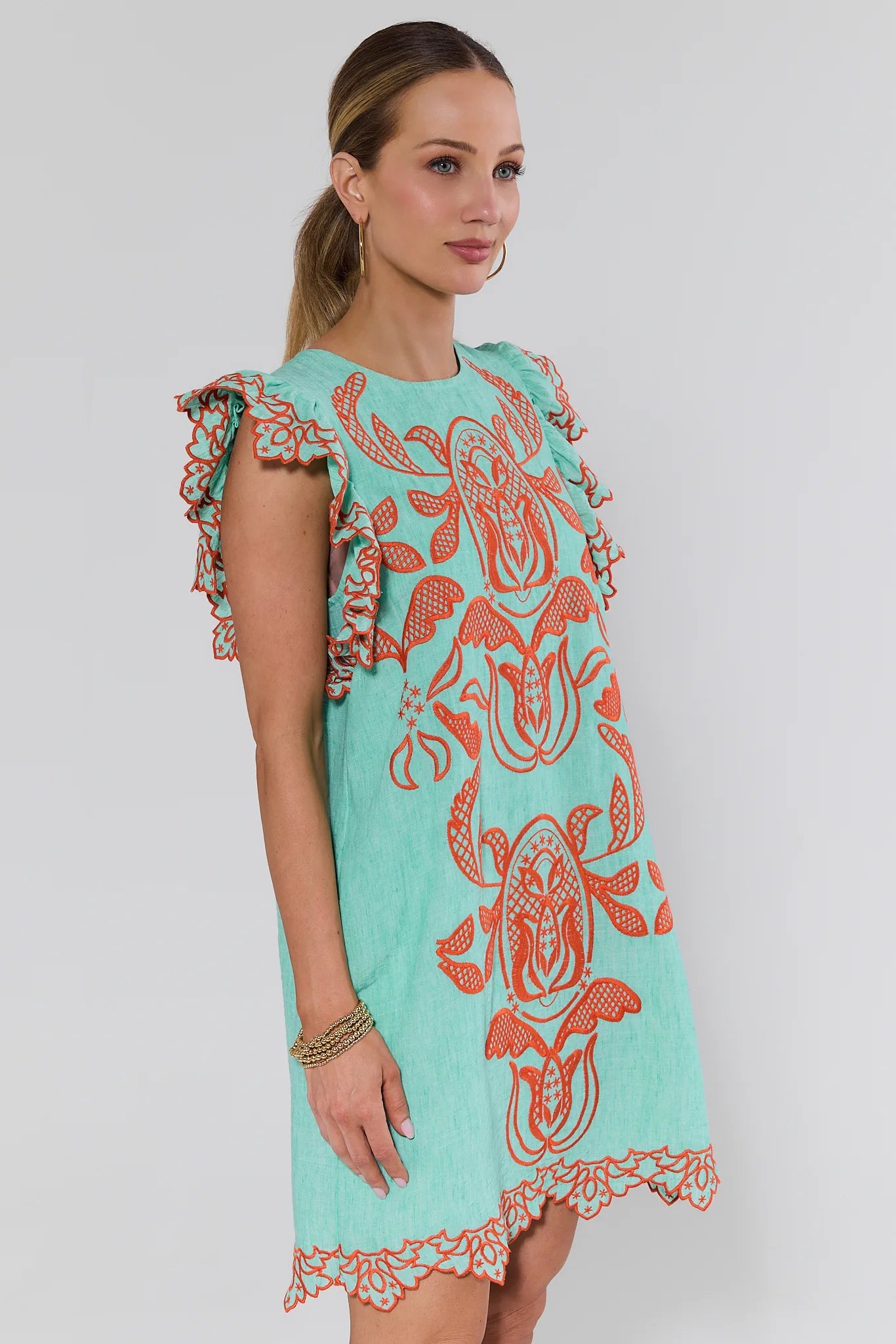 Woman wearing a turquoise dress with red patterns on a background