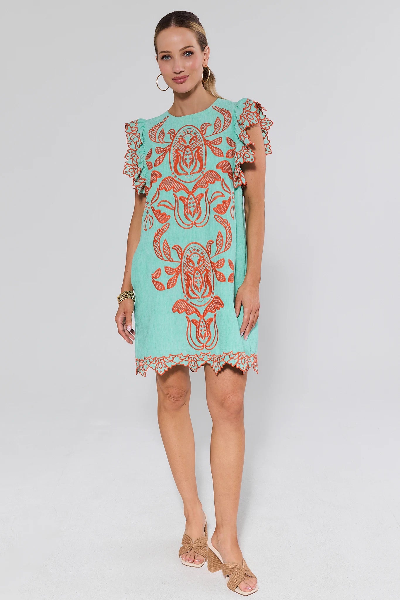 Woman wearing a turquoise dress with red patterns on a background