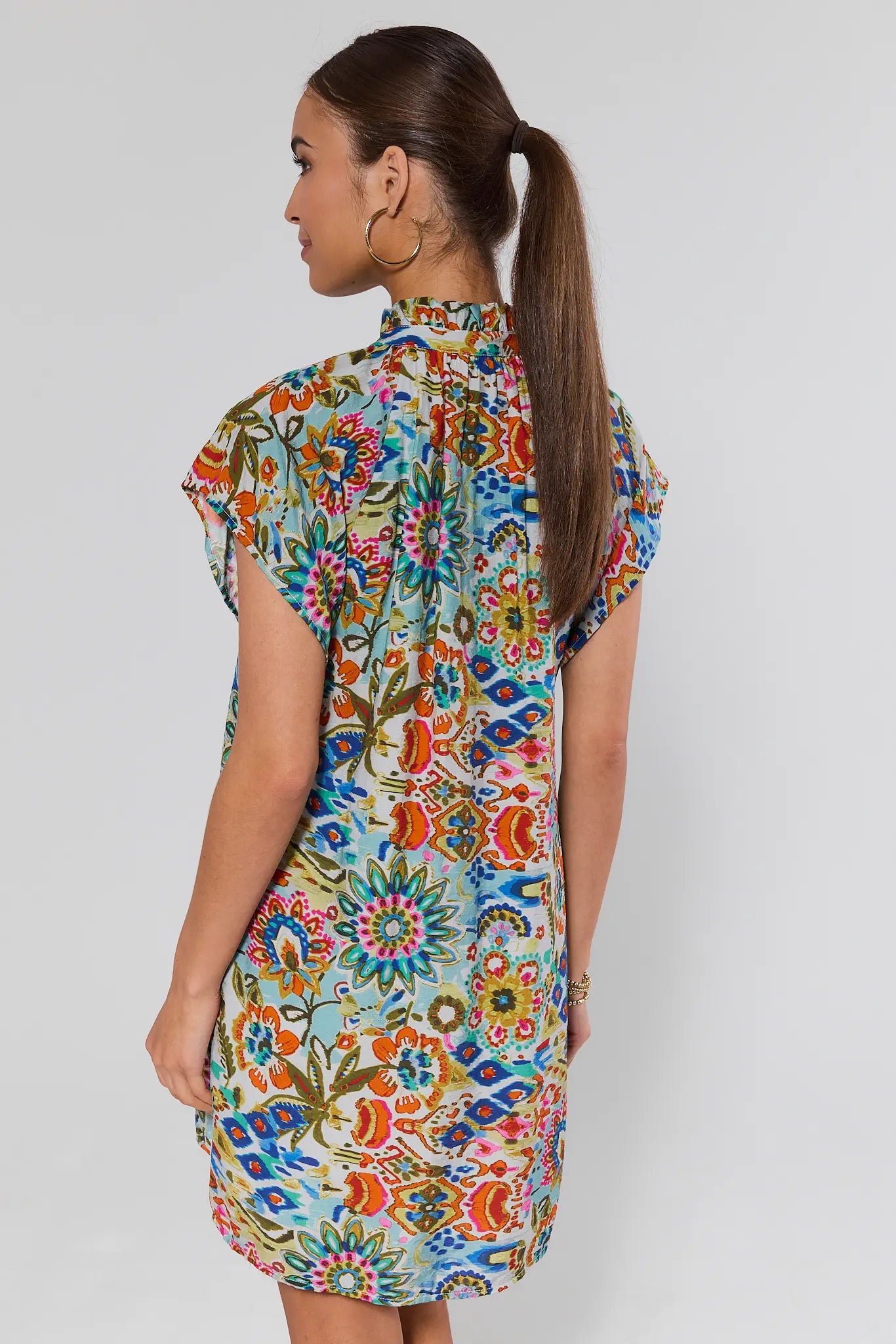 Woman wearing a colorful floral dress on a plain background