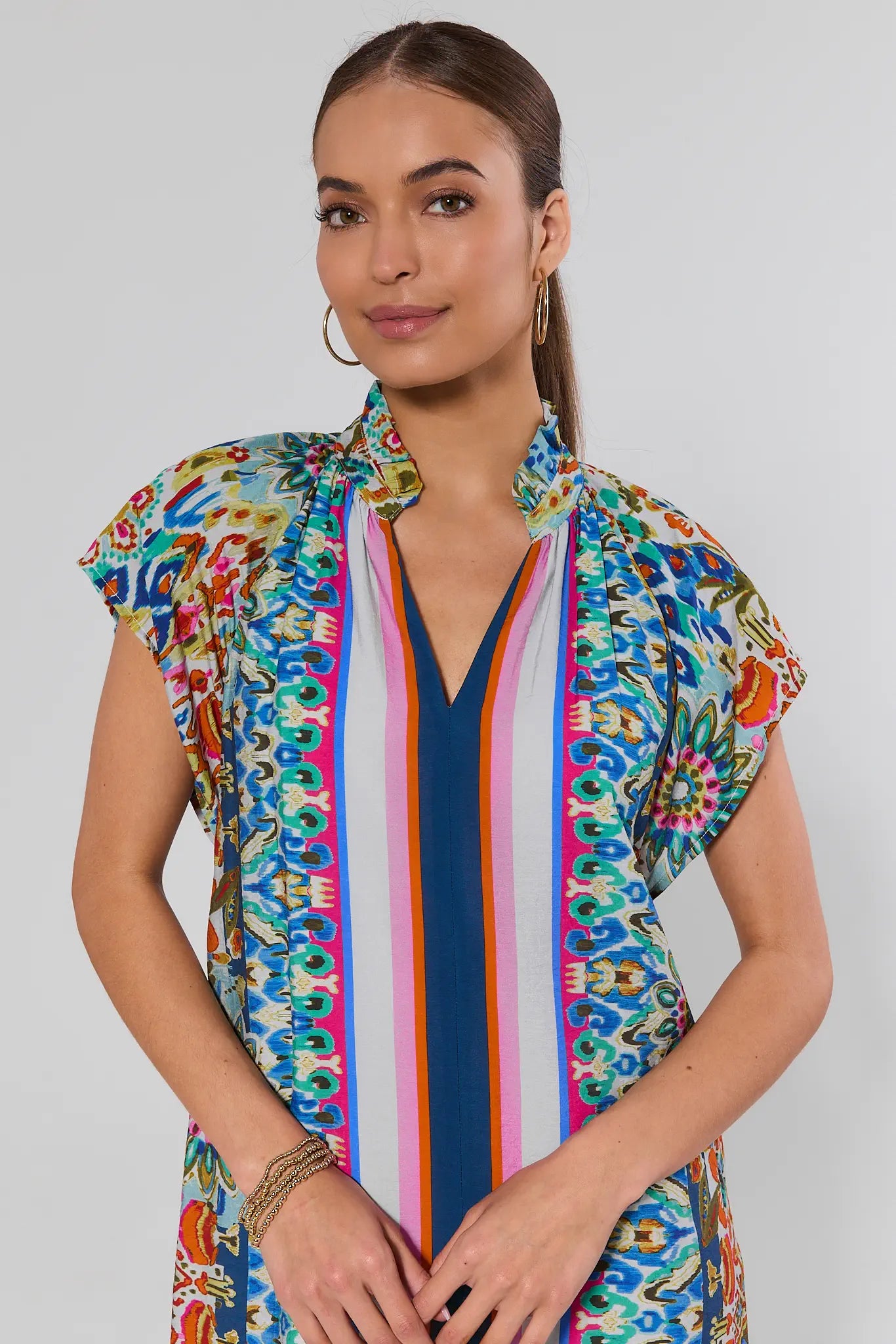 Woman wearing a colorful patterned dress with a plain background