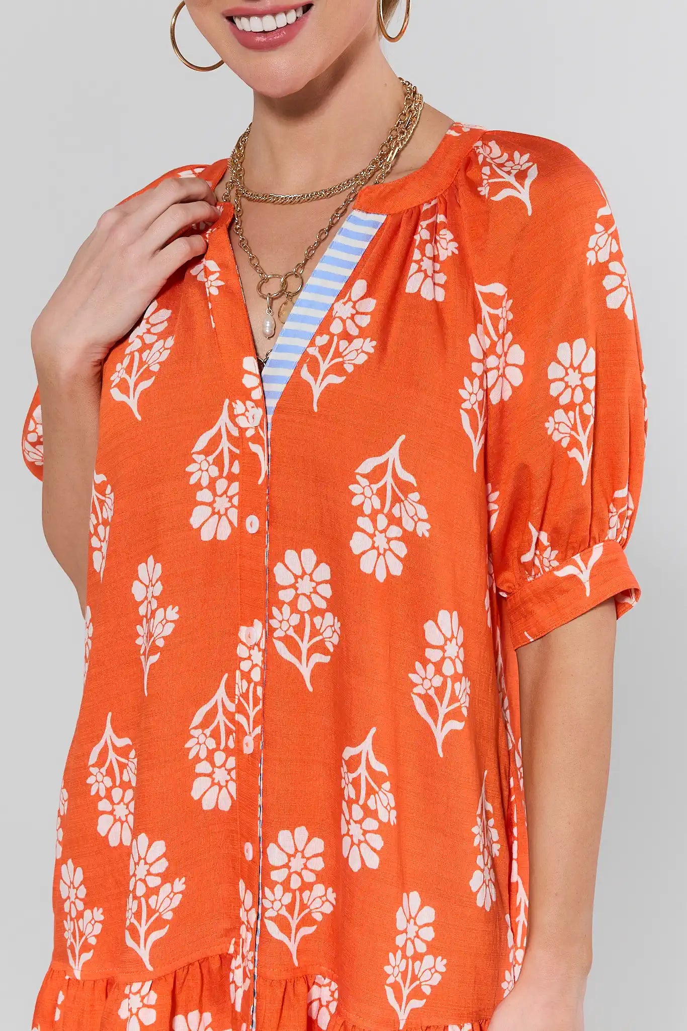 Woman wearing an orange floral dress with a plain background