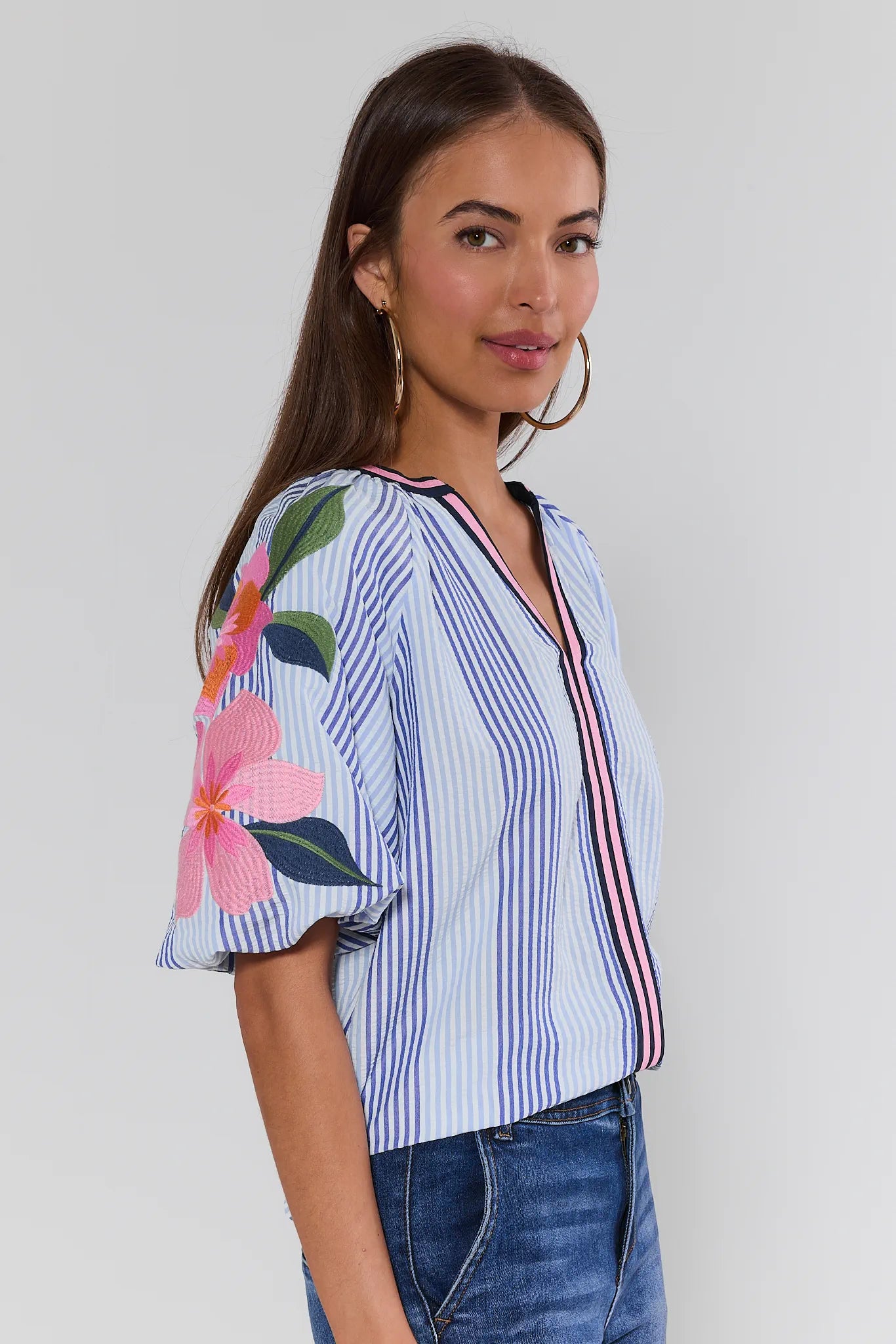 Woman wearing a striped shirt with floral sleeves against a plain background