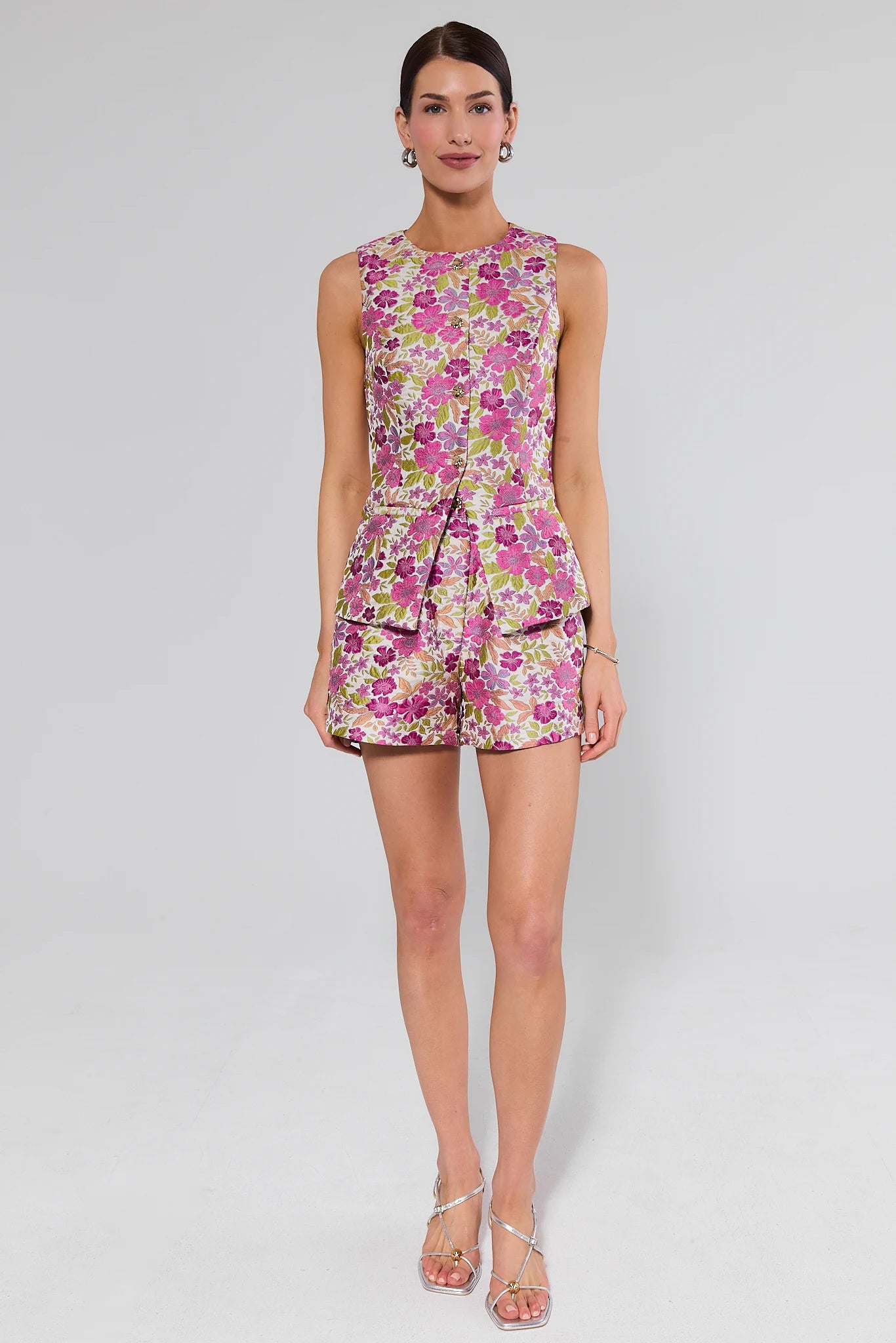 Woman wearing a floral top and shorts on a plain background