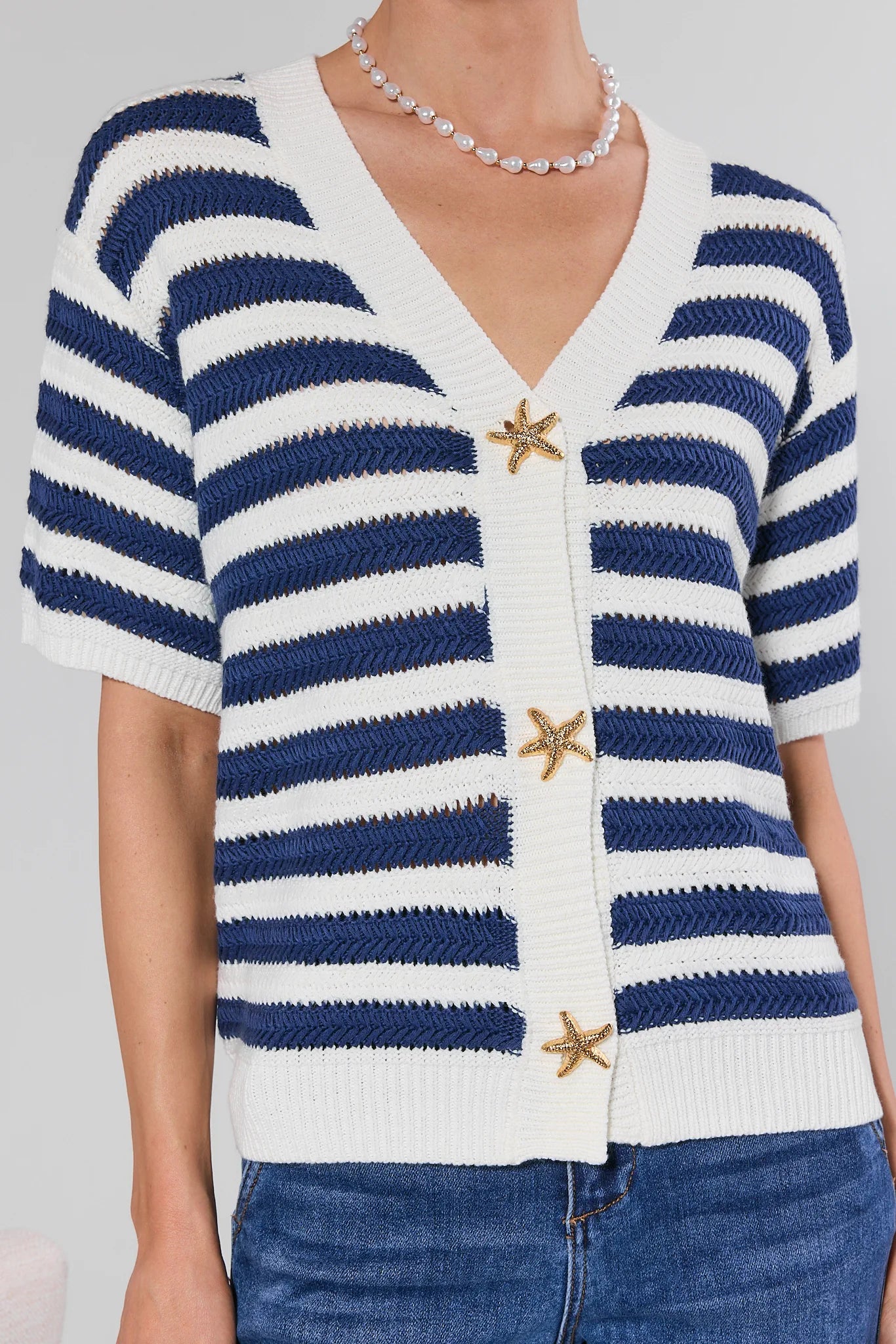 Blue and white striped cardigan with starfish buttons on a plain background