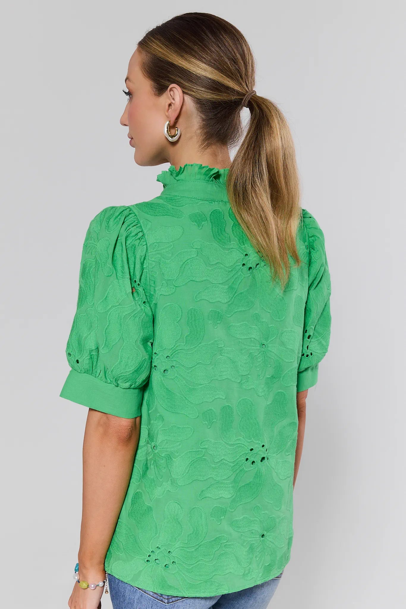 Woman wearing a green blouse with floral patterns on a plain background