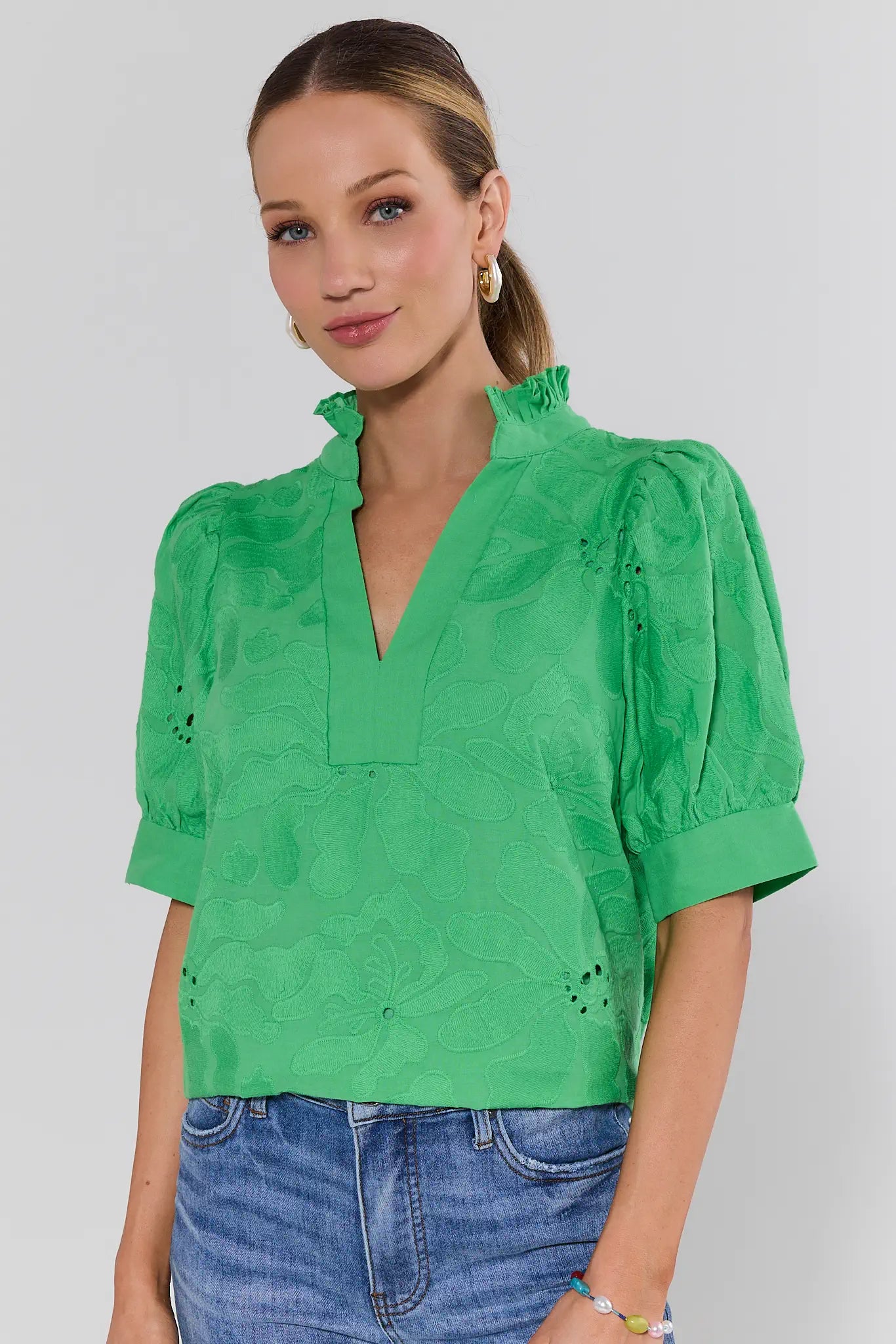 Woman wearing a green blouse with puffed sleeves against a plain background