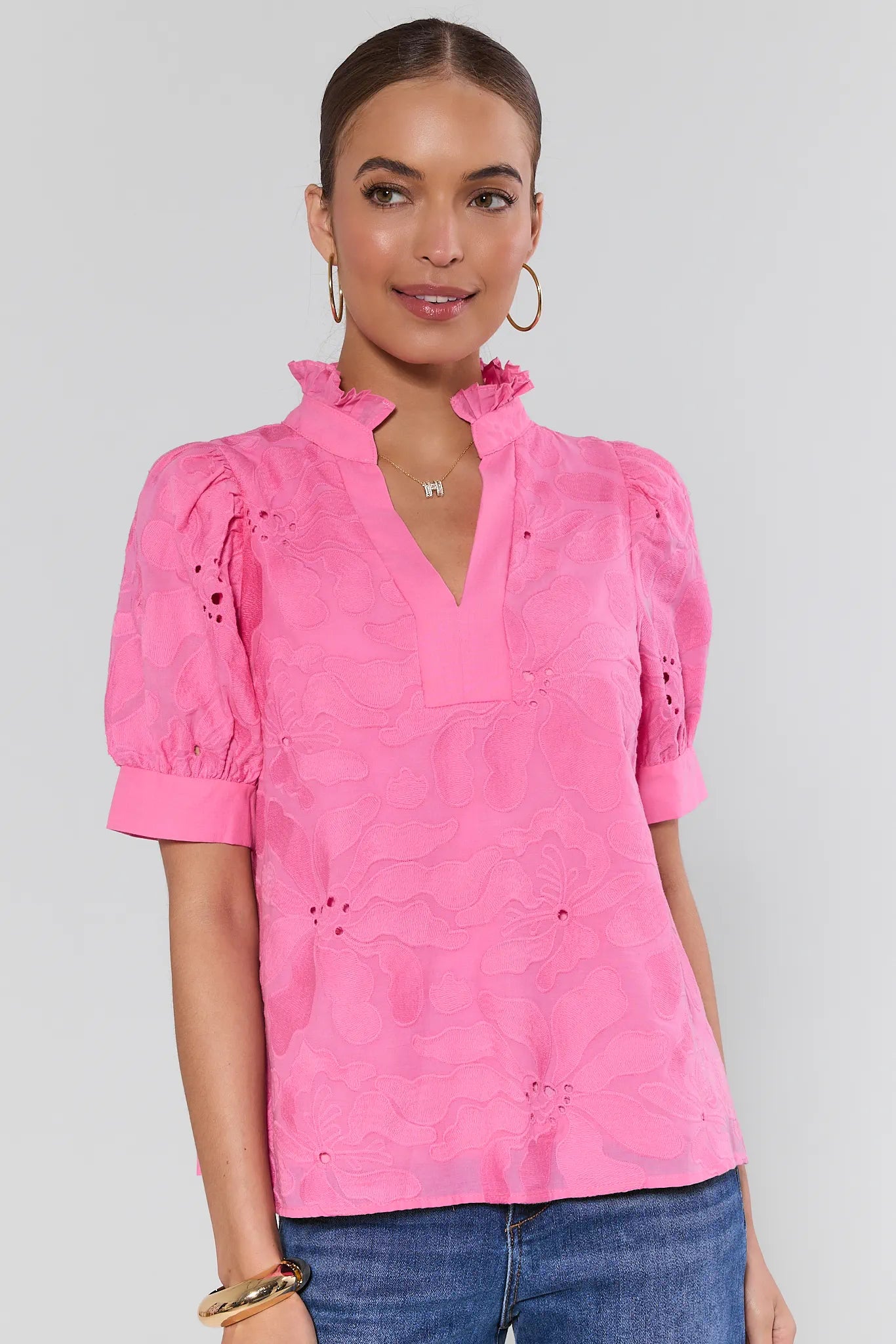 Woman wearing a pink blouse with ruffled details on a white background