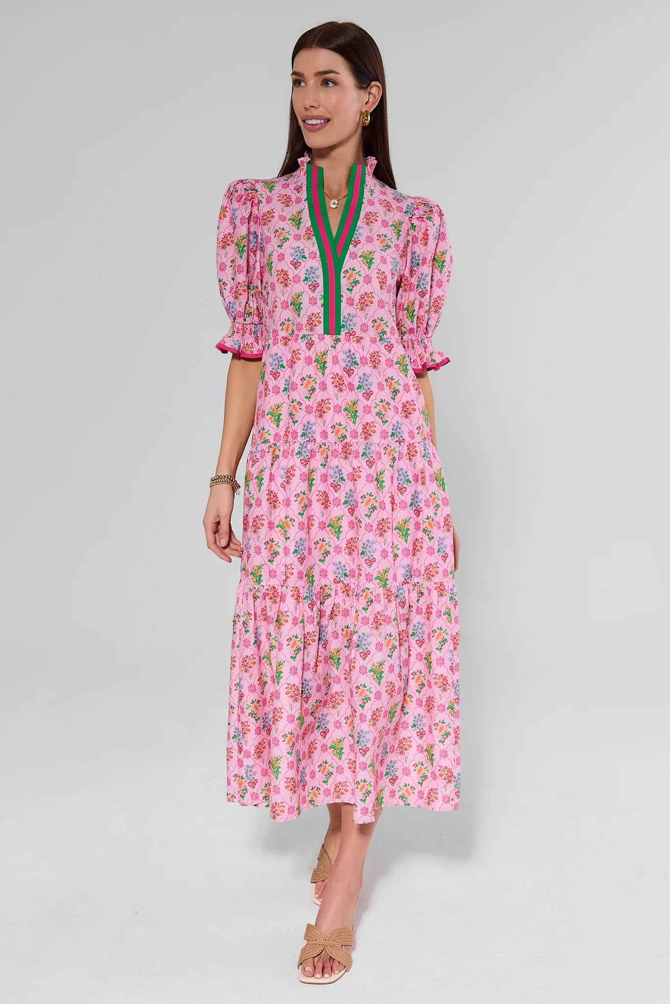 Woman wearing a pink floral dress with green accents on a gray background