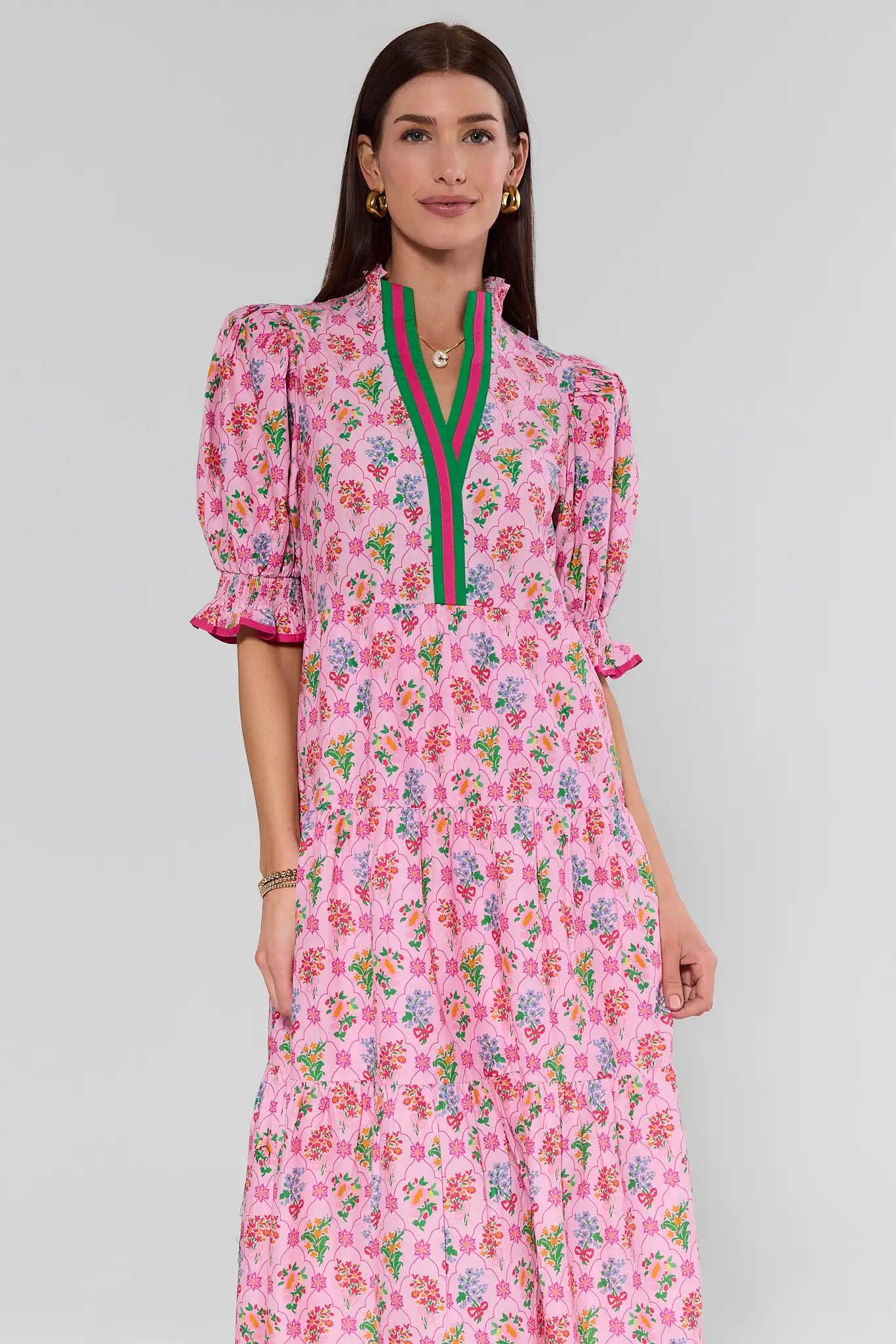 Woman wearing a pink floral dress with green accents on a gray background