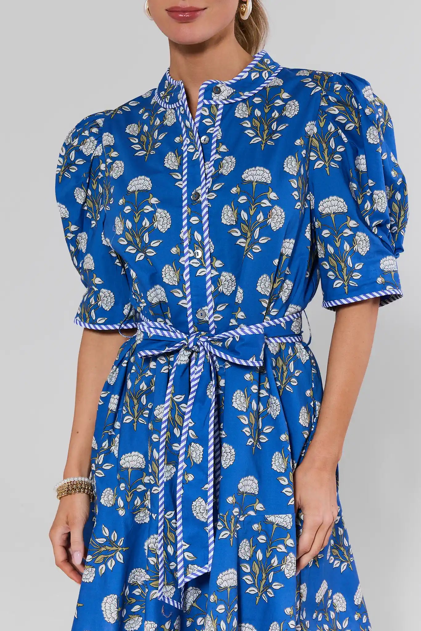 Woman wearing a blue floral dress against a gray background