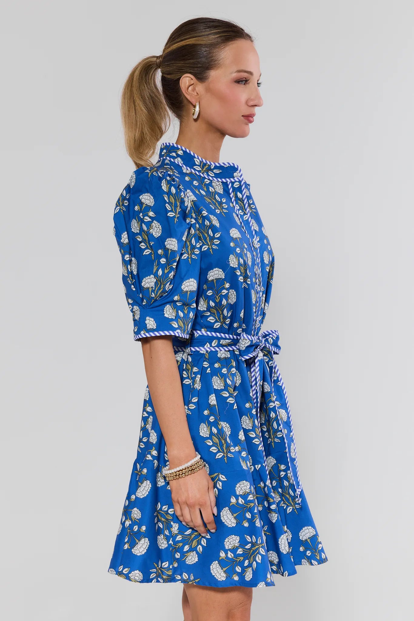 Woman wearing a blue floral dress on a plain background