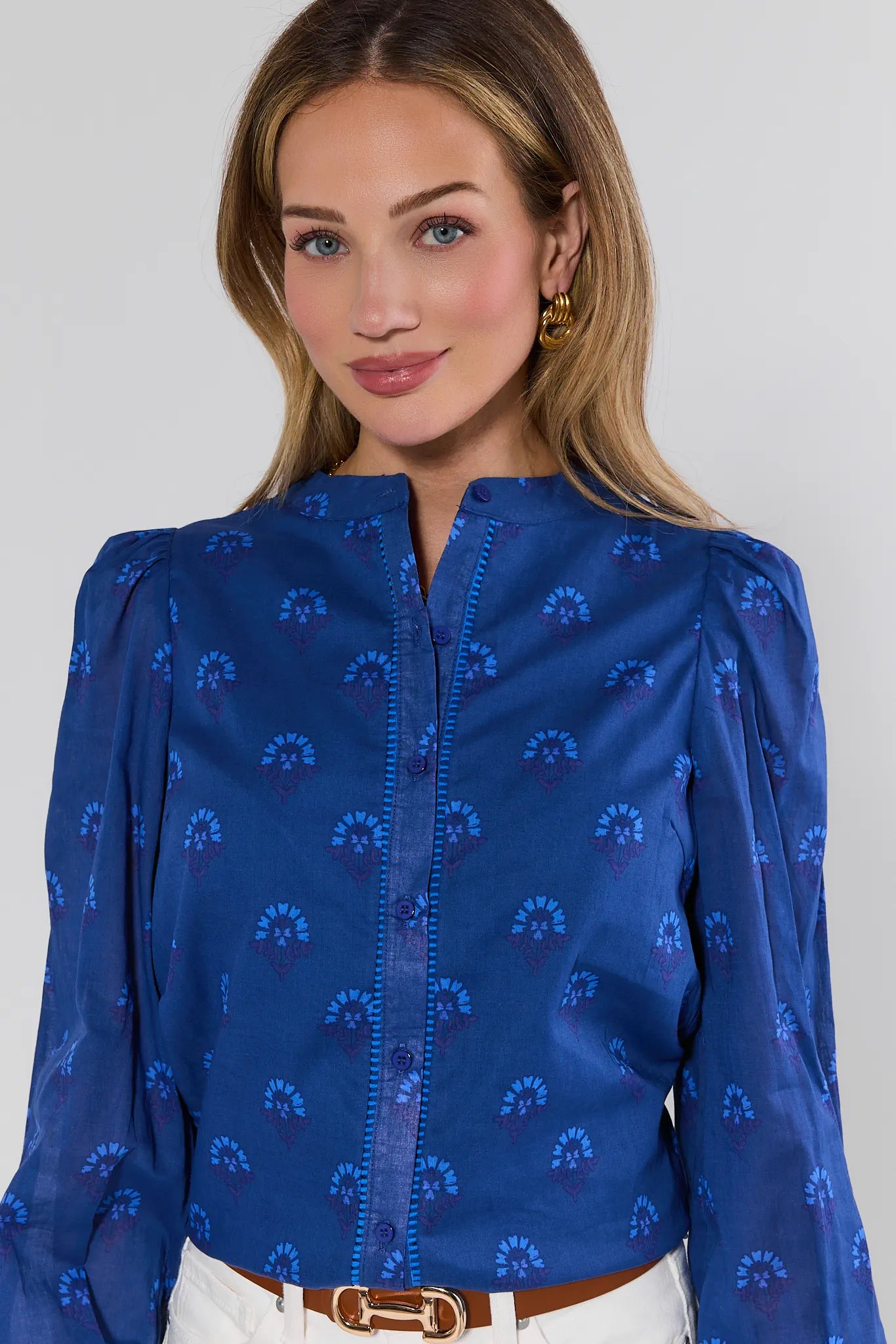 Woman wearing a blue patterned blouse against a plain background