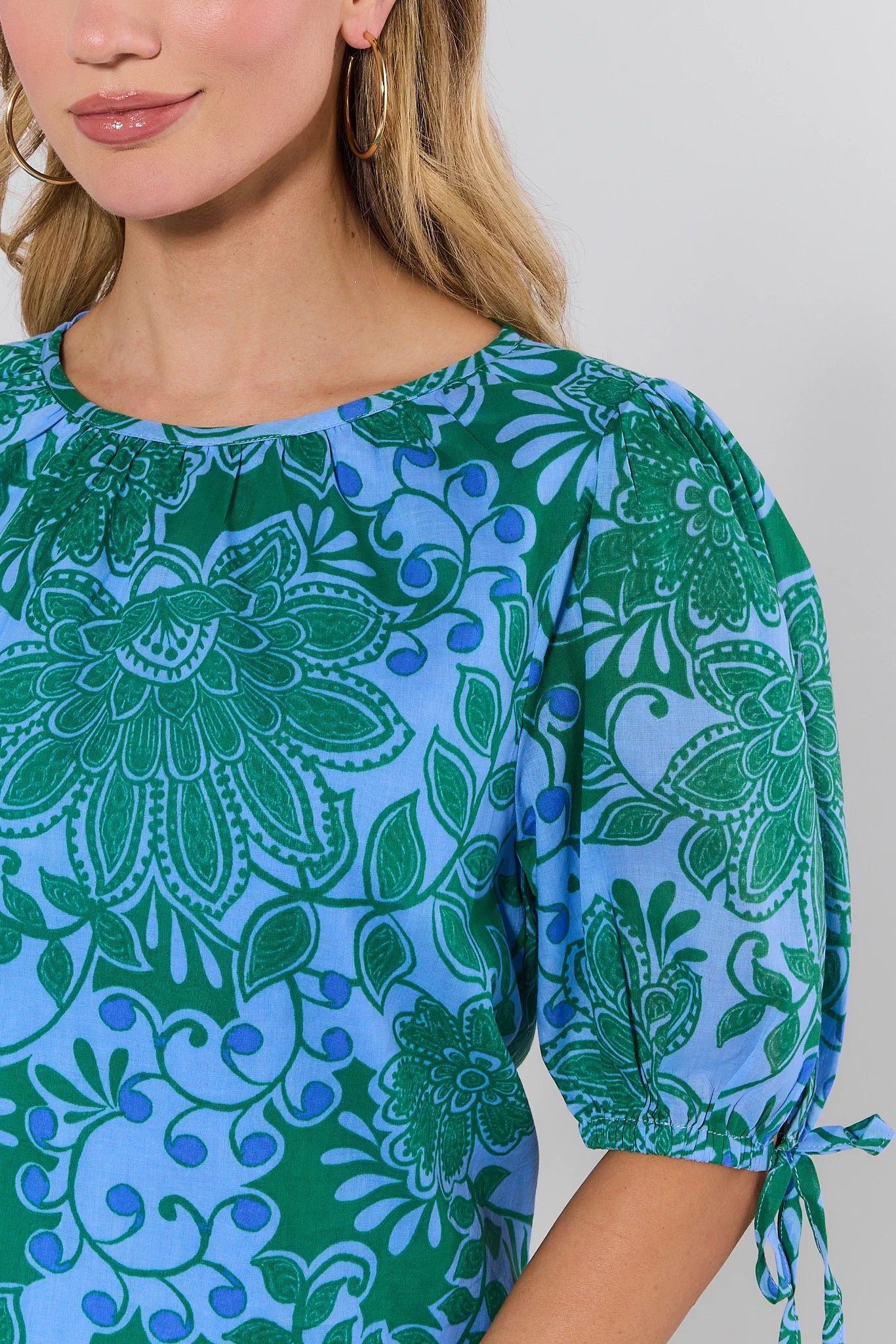 Woman wearing a blue and green patterned dress with a plain background