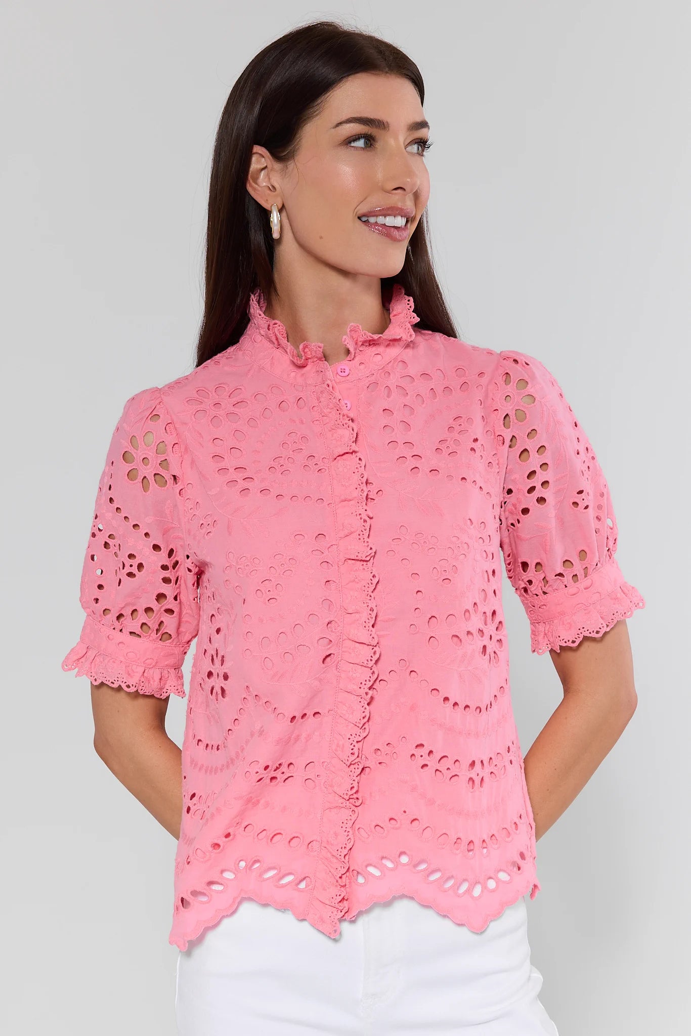 Woman wearing a pink lace blouse against a plain background