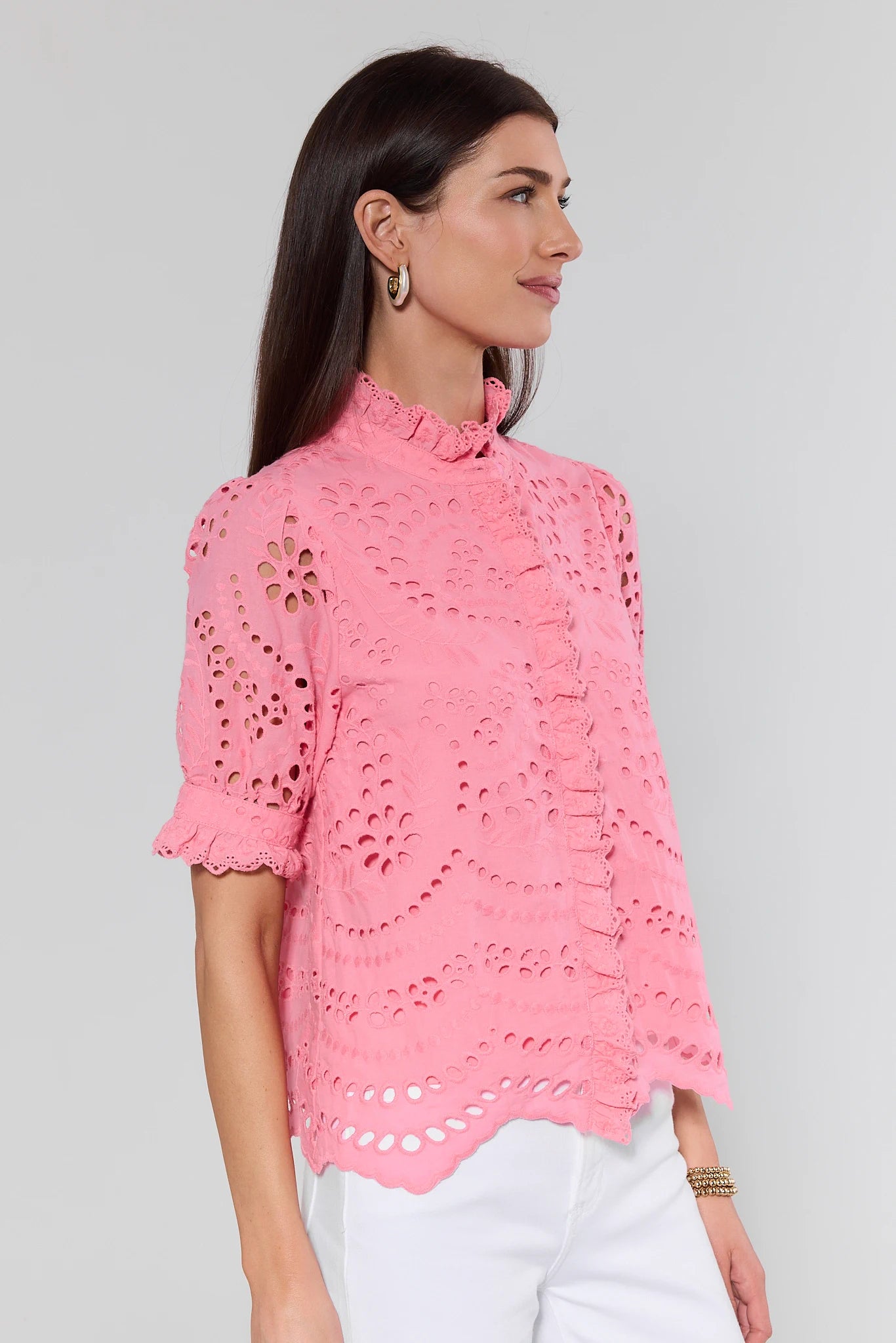 Woman wearing a pink lace top against a gray background
