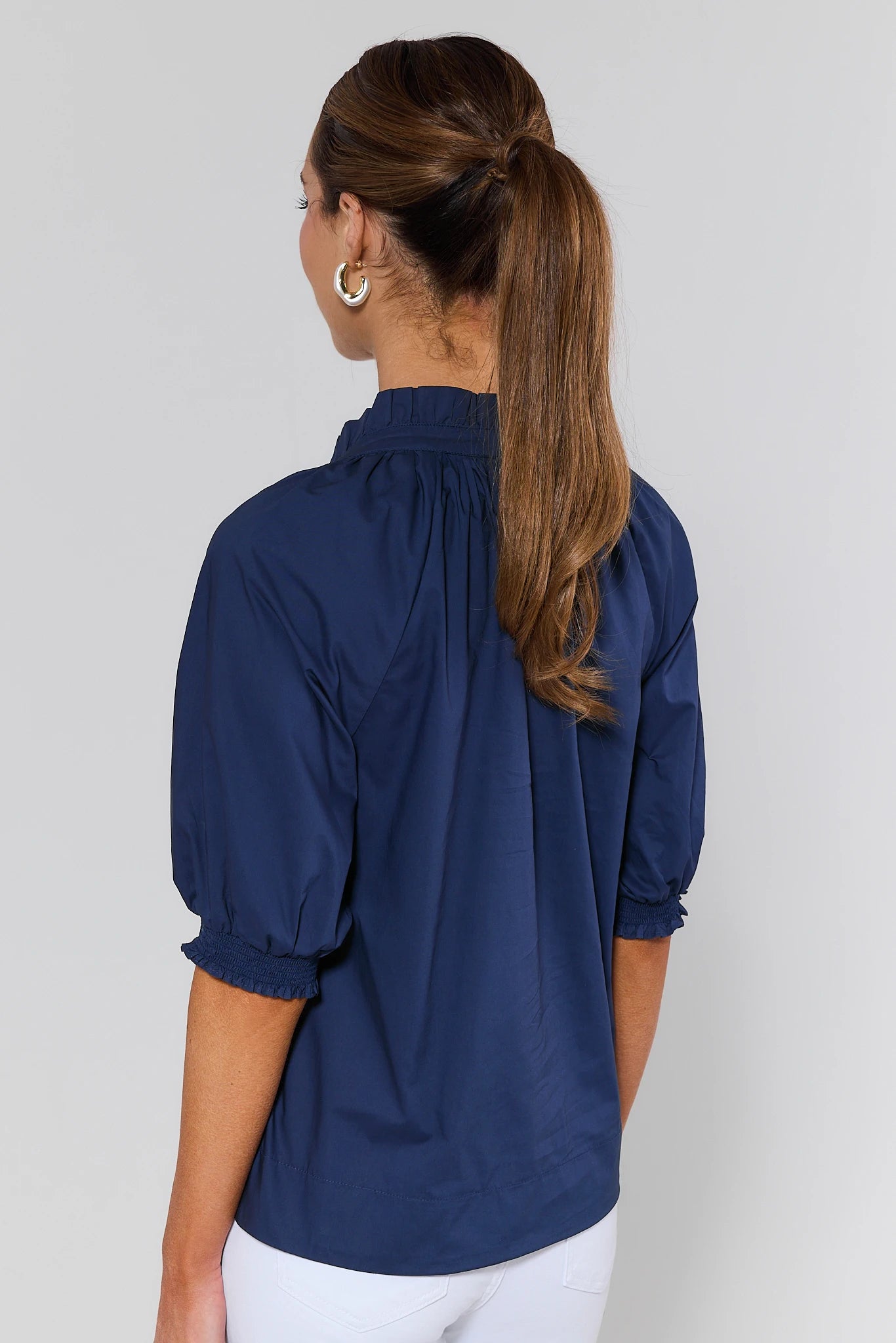 Woman wearing a navy blue blouse with puffed sleeves against a plain background