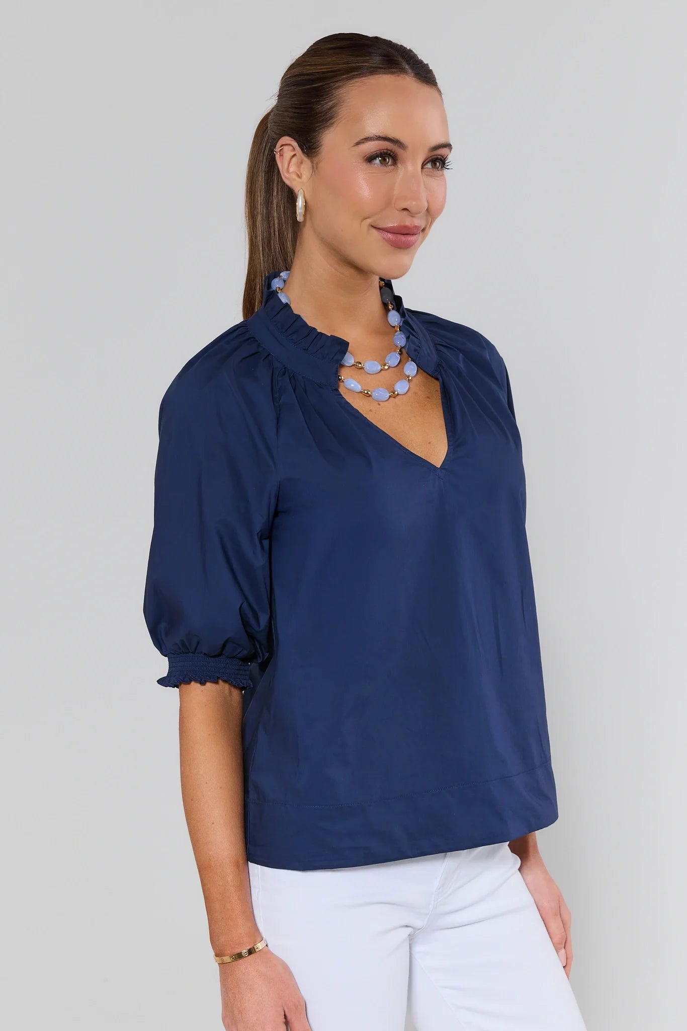Woman wearing a navy blue blouse with a plain background