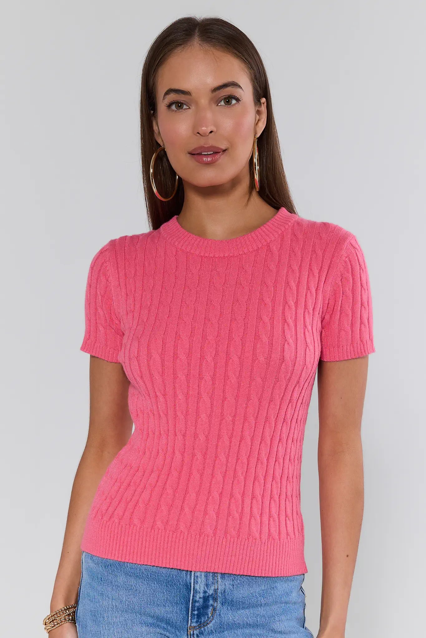 Woman wearing a pink knitted sweater against a plain background