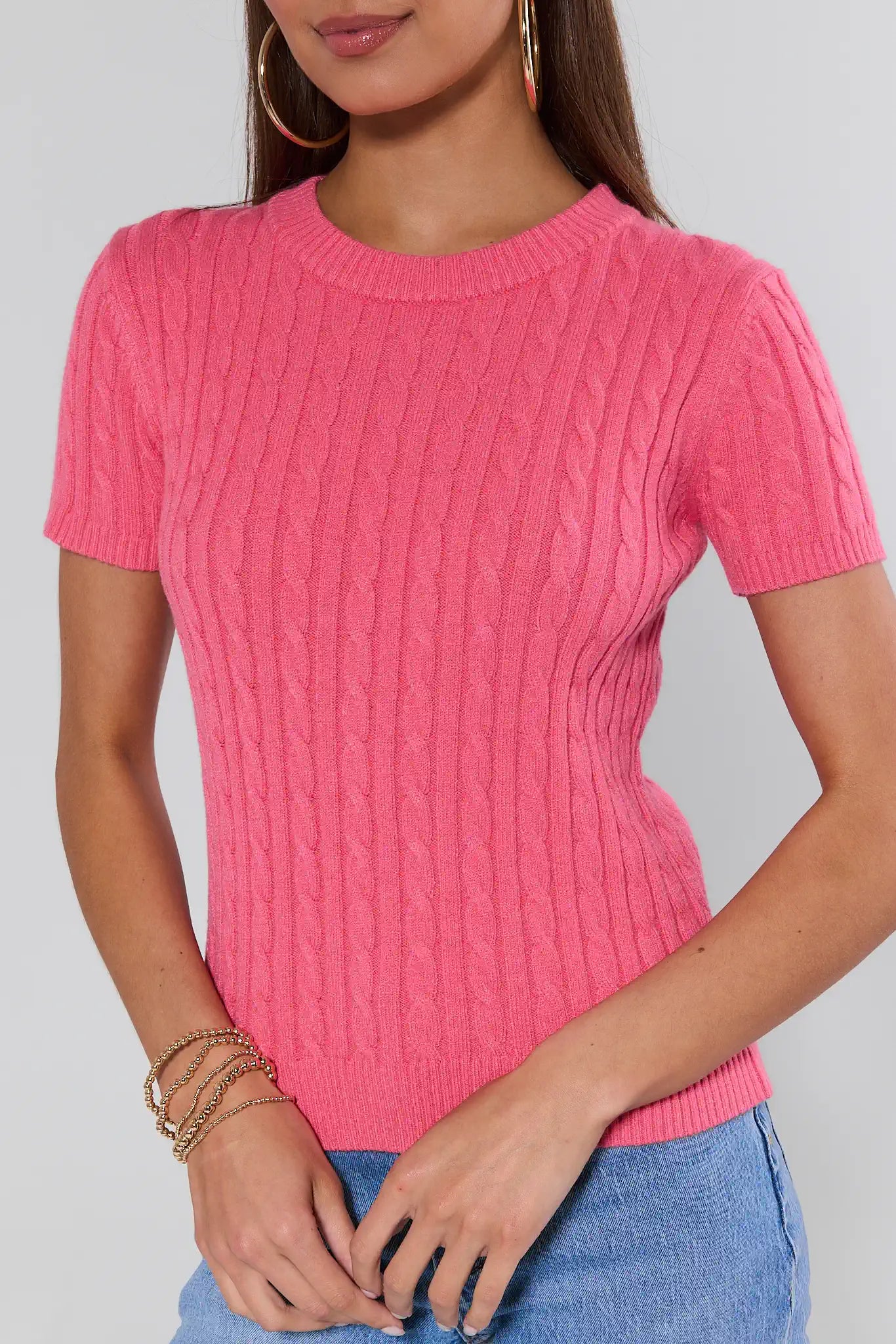 Person wearing a pink knitted top with a plain background