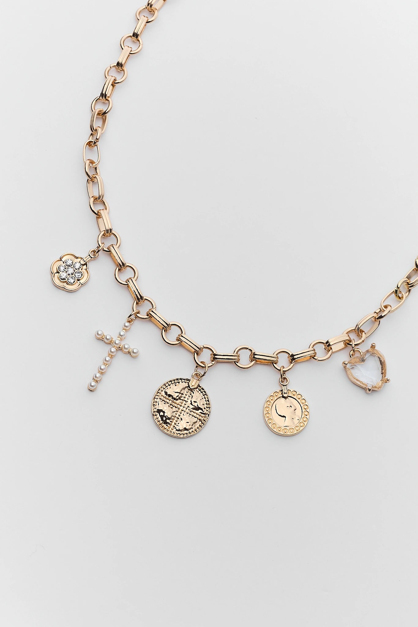 close up gold necklace with various charms on a light gray background