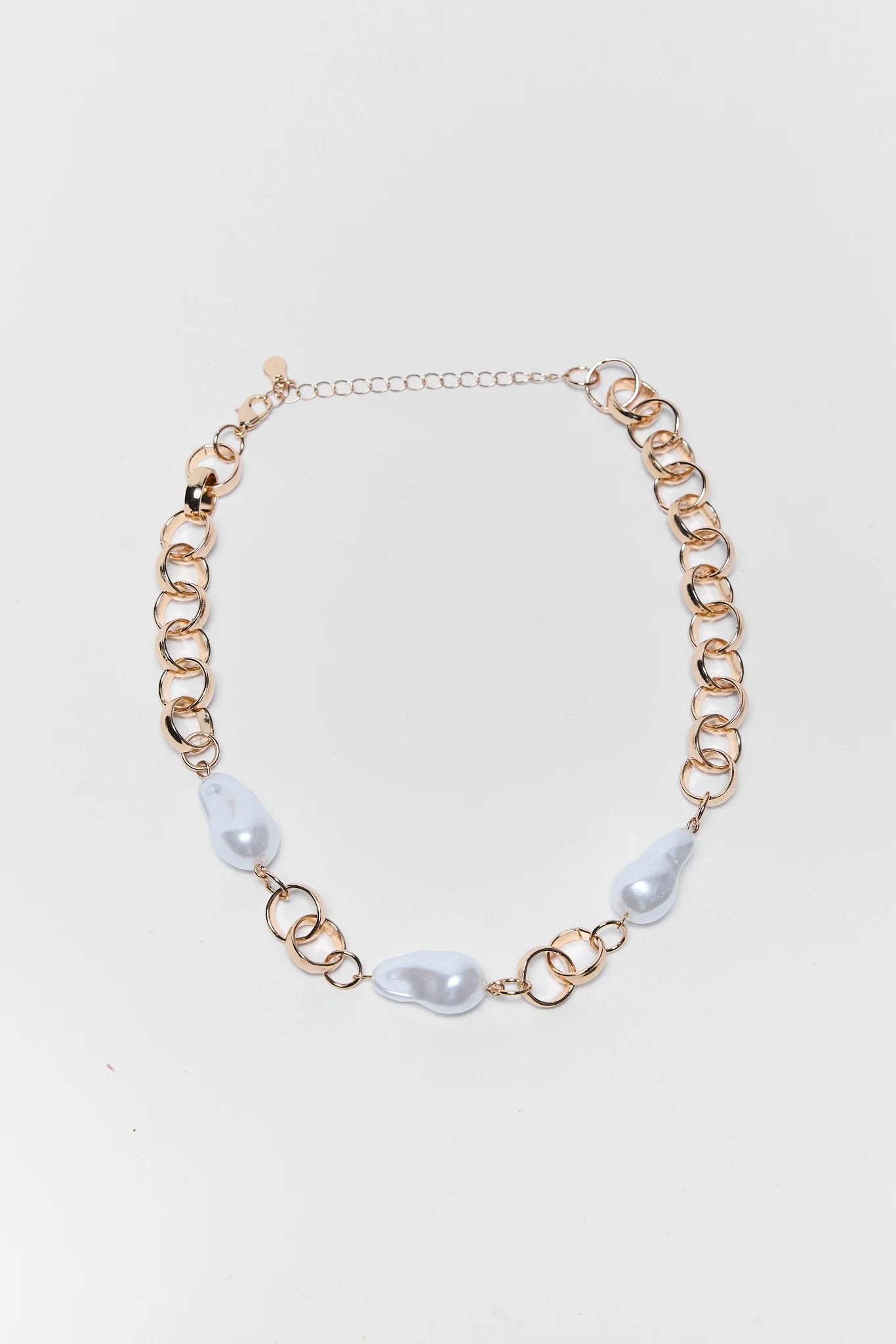 Gold chain necklace with pearl-like beads on a white background