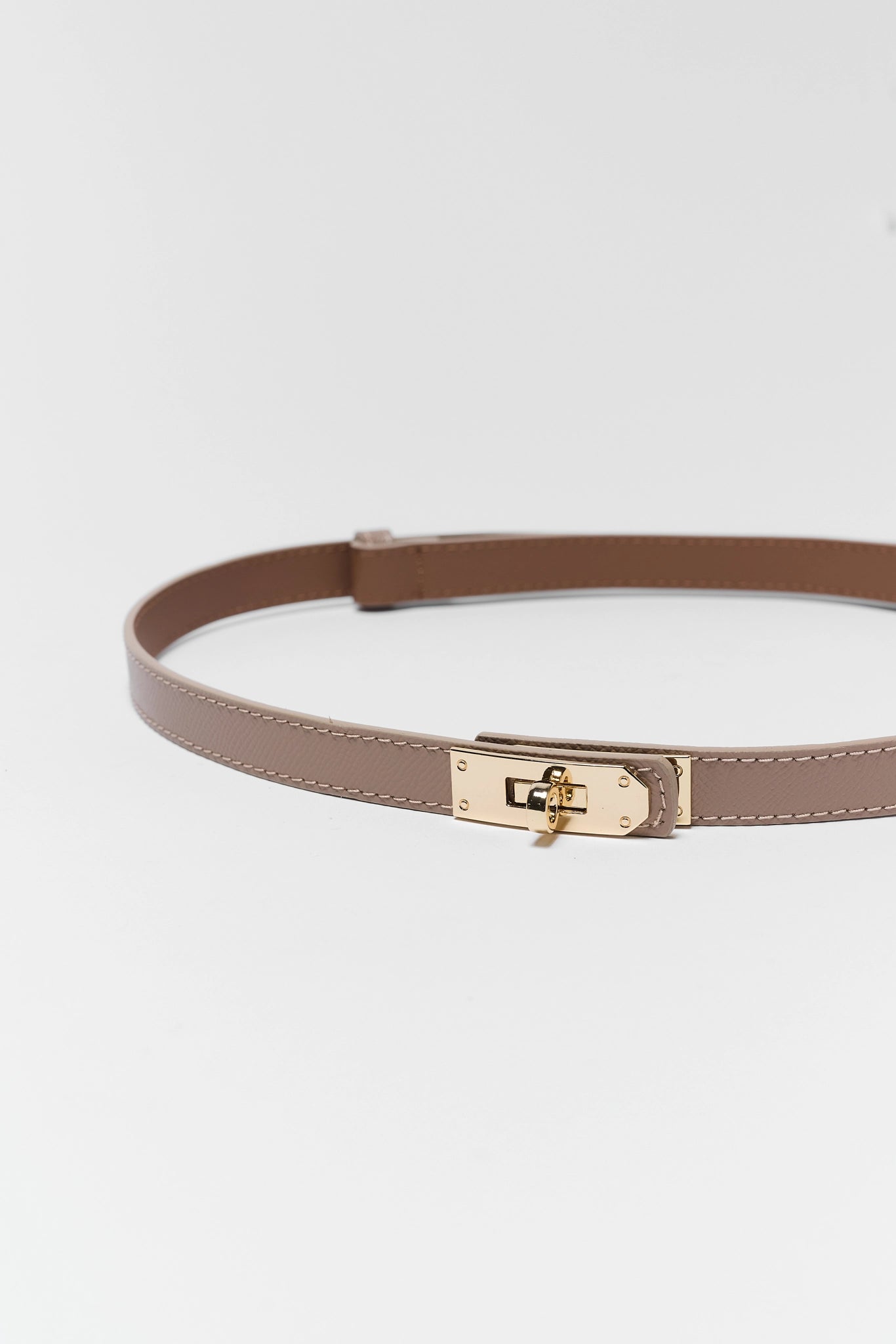 close up Brown belt with a gold buckle on a light gray background