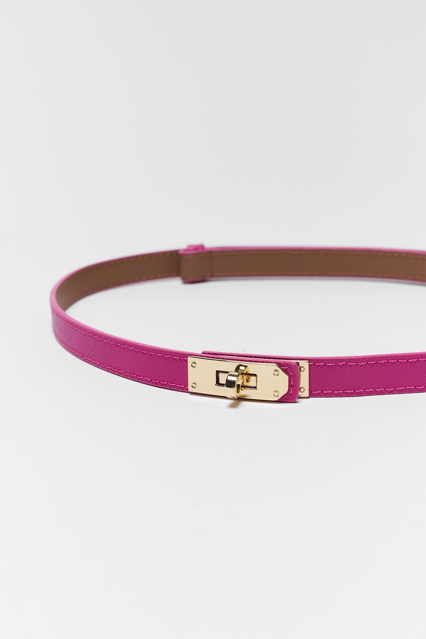 close up Pink belt with a gold buckle on a light gray background