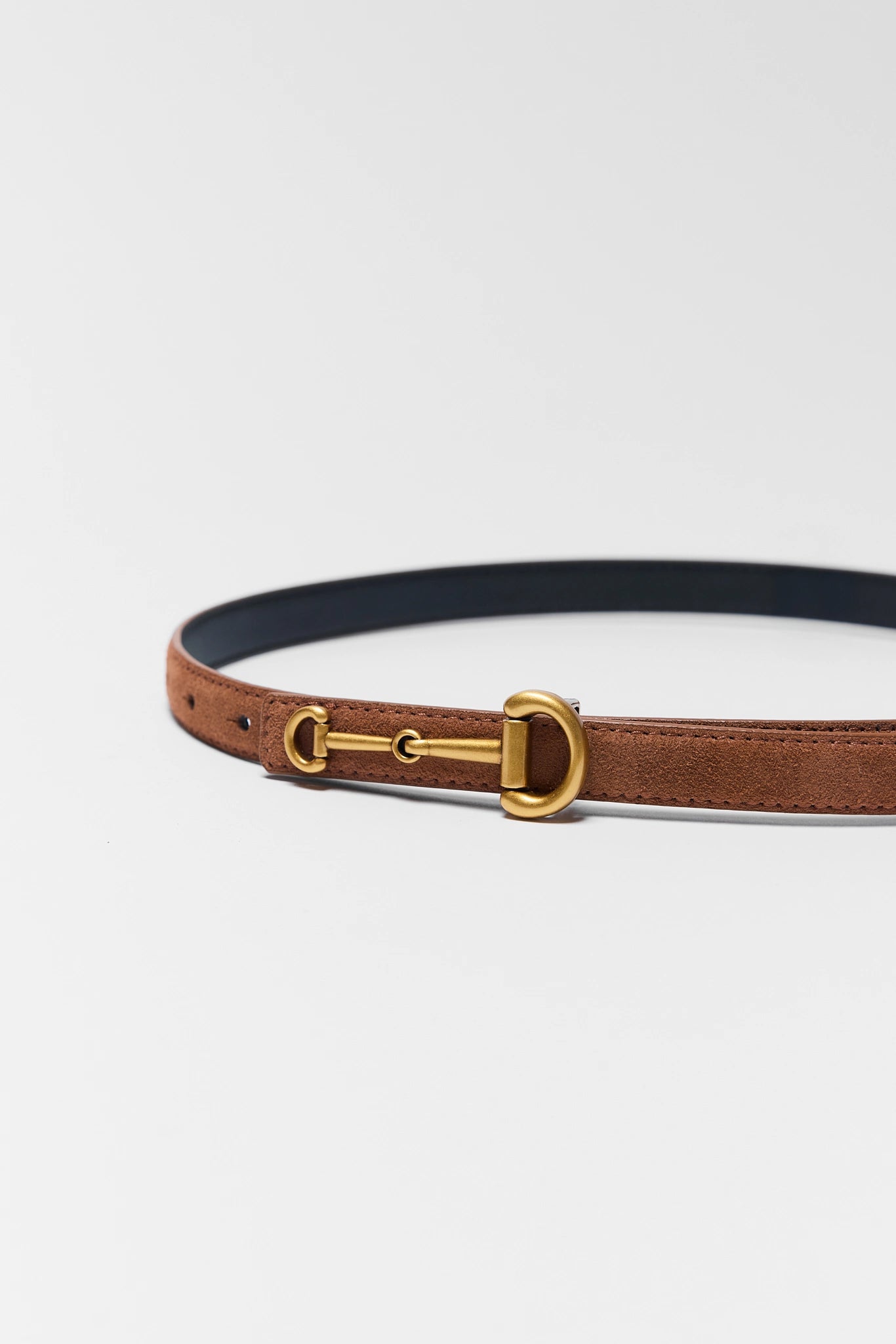 Brown leather belt with gold buckle on a light gray background