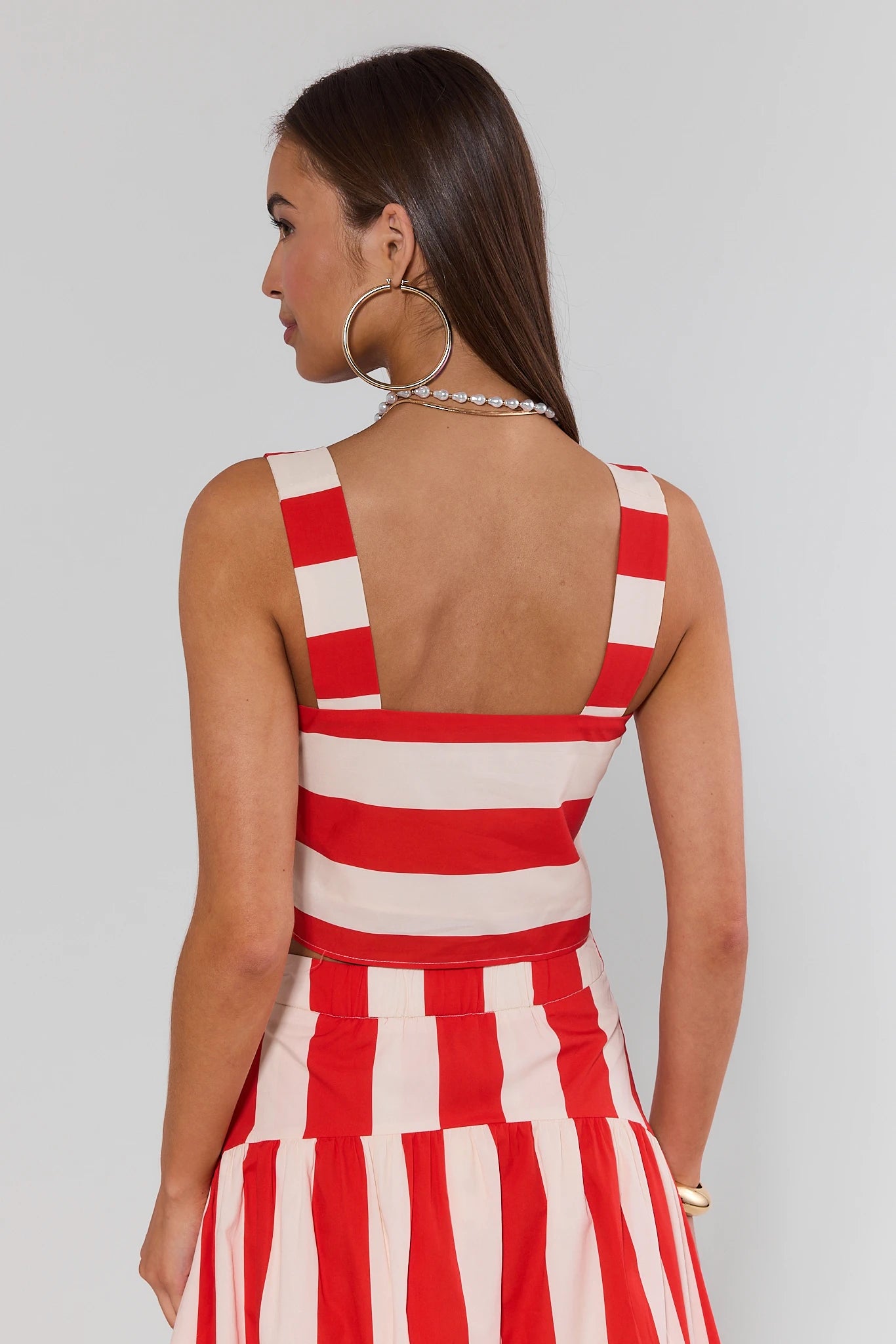 Woman wearing a red and white striped dress against a plain background
