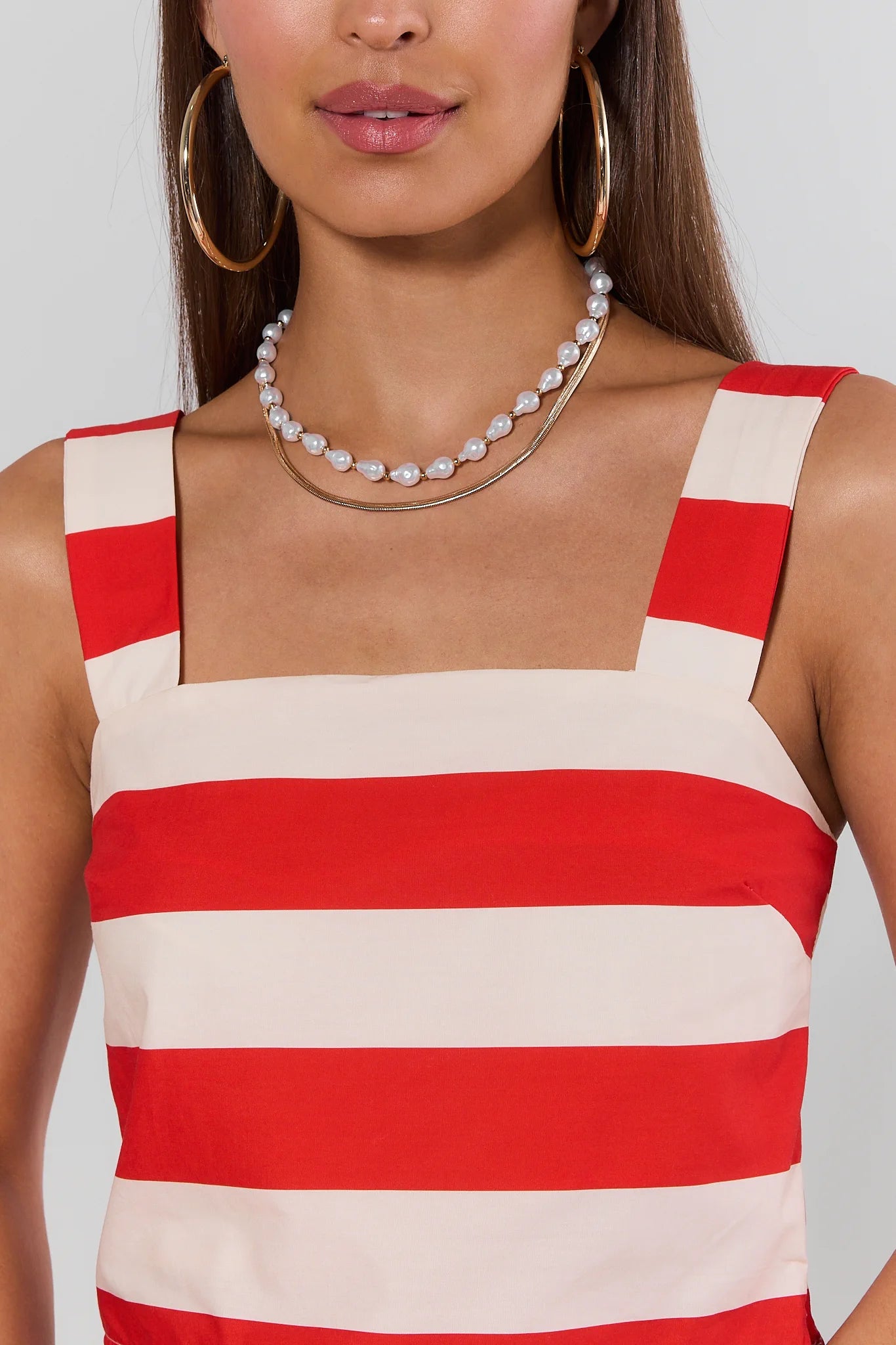 Woman wearing a red and beige striped top with a plain background