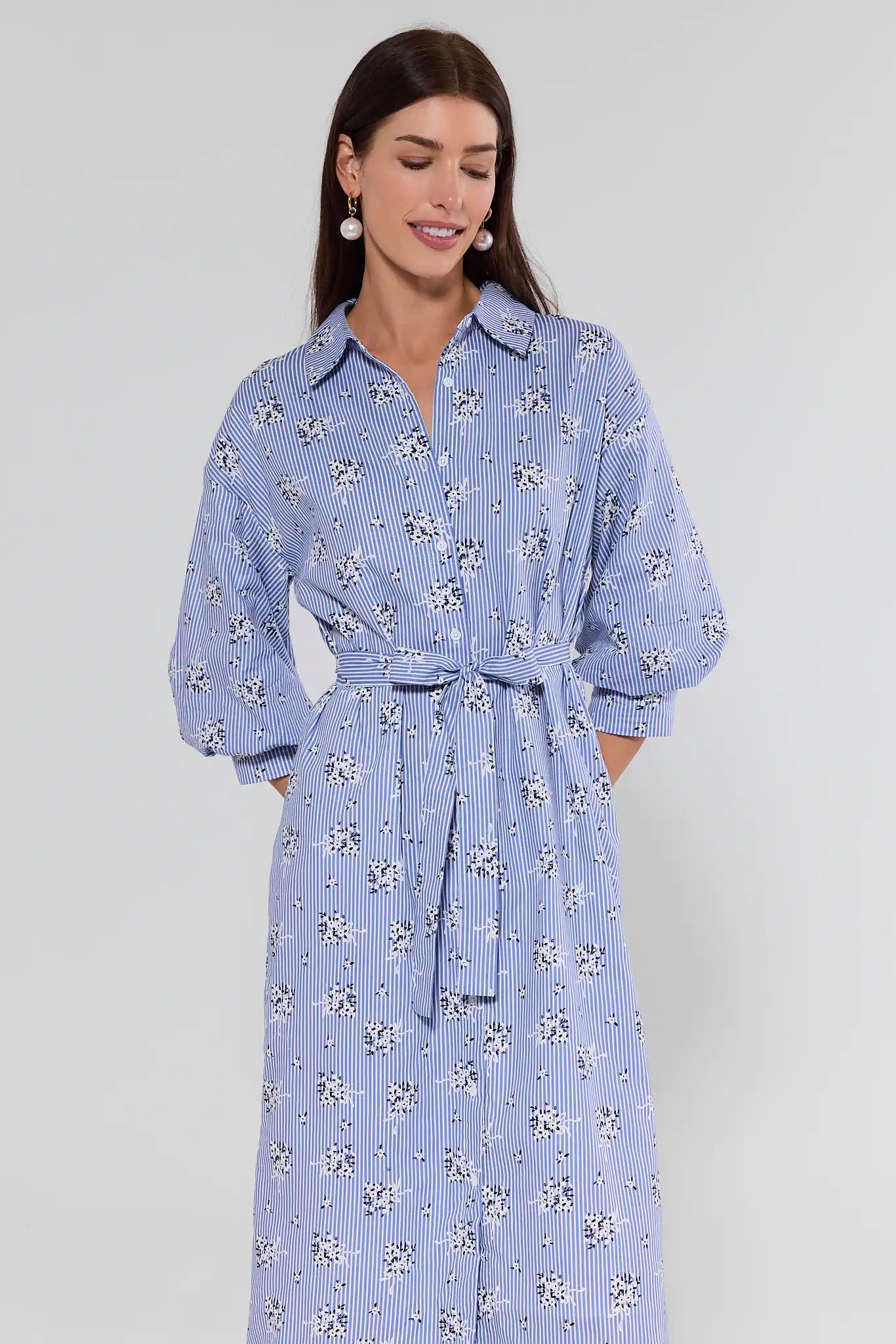 Woman wearing a blue floral dress on a gray background